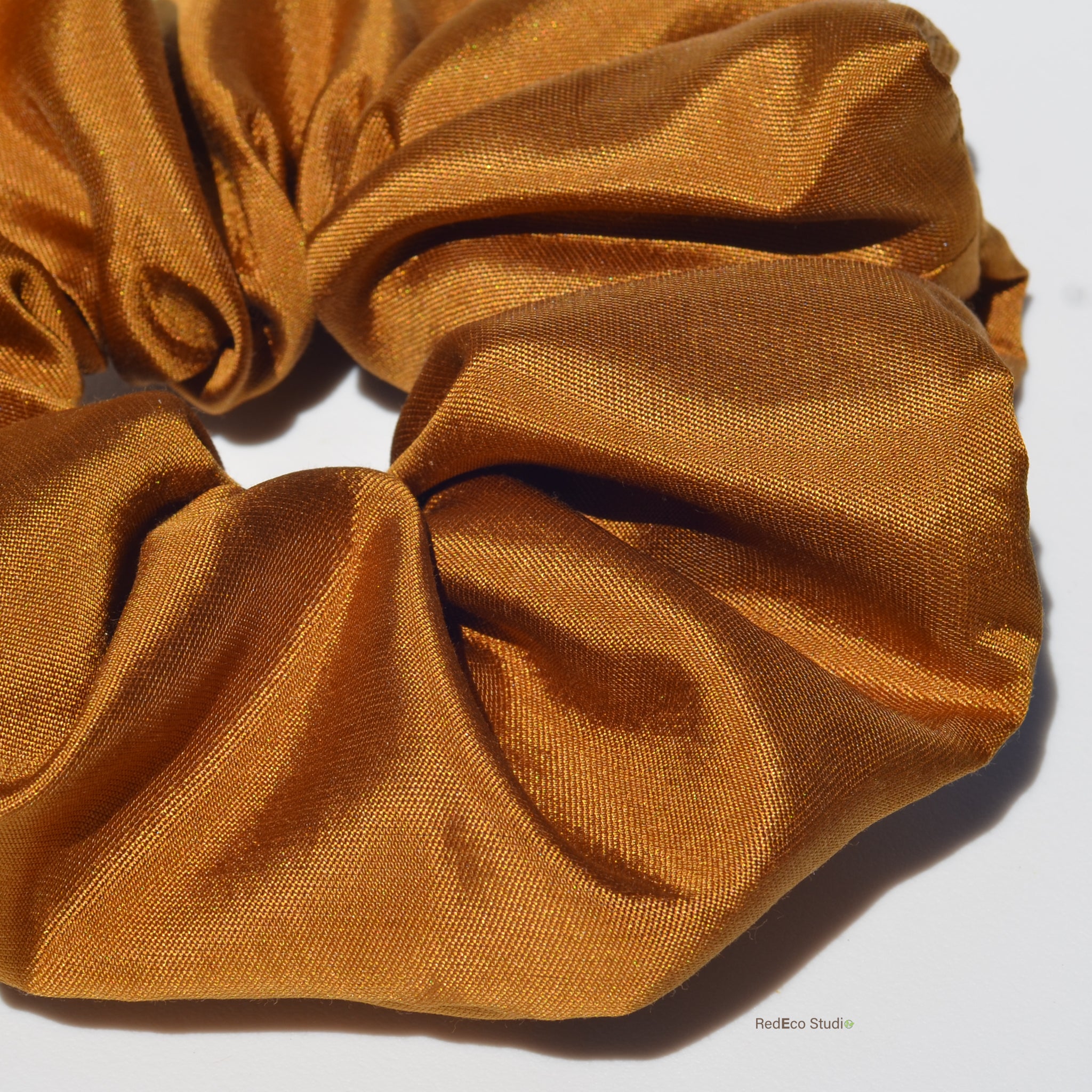 Close-up of a mustard yellow scrunchie on a white background