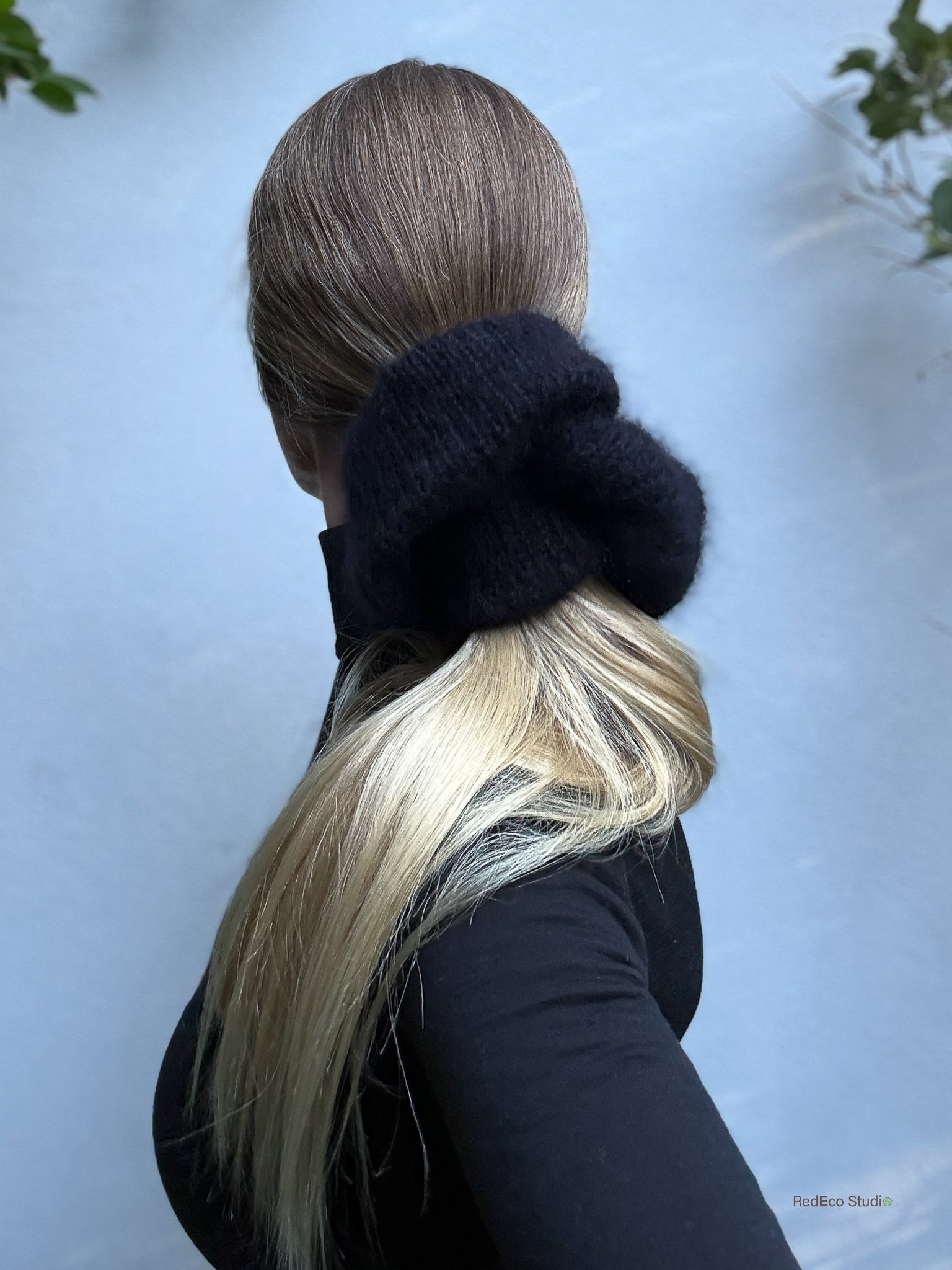Person with a black scrunchie in their hair against a light blue background