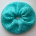 Large hand knitted bright blue scrunchie on a white background