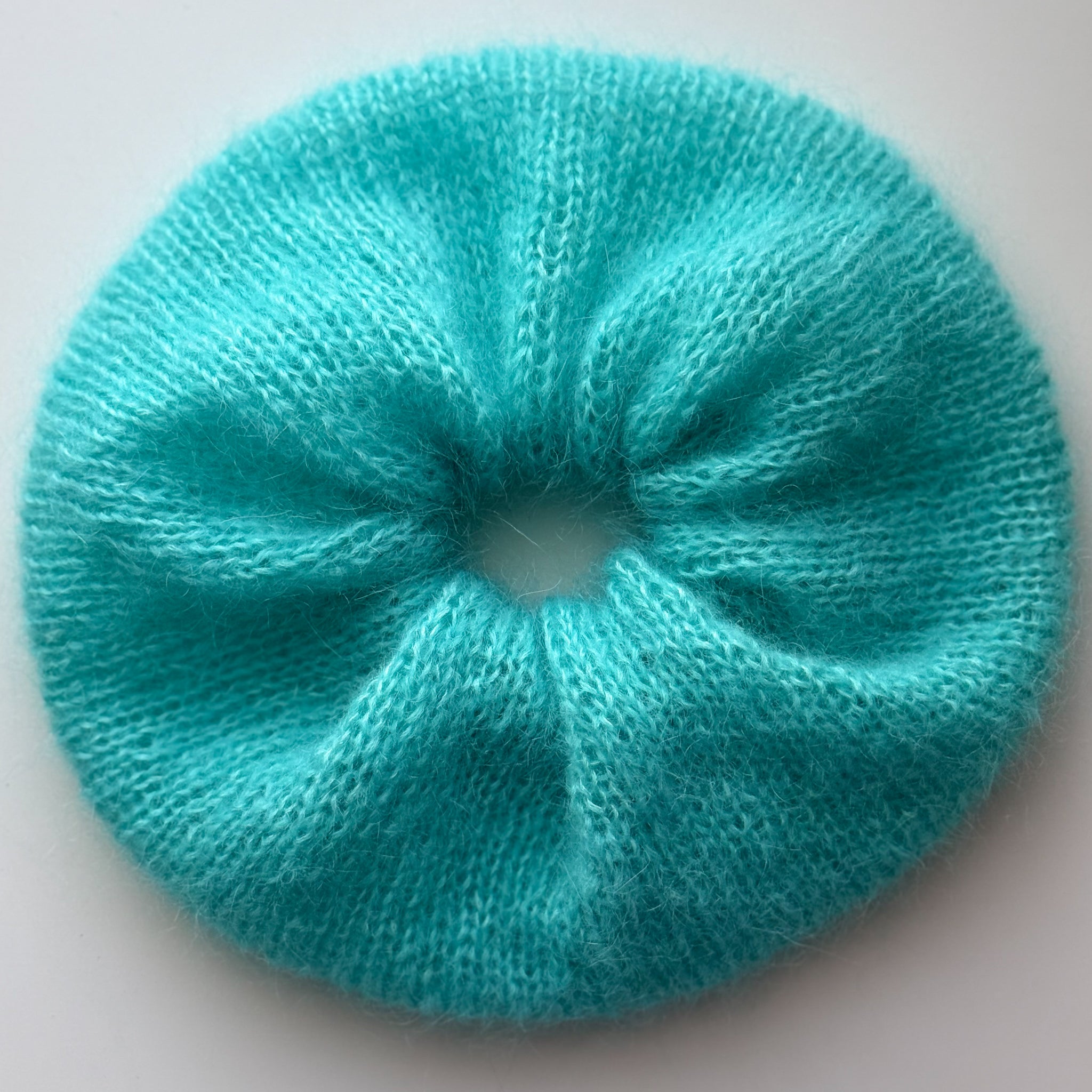 Large hand knitted bright blue scrunchie on a white background