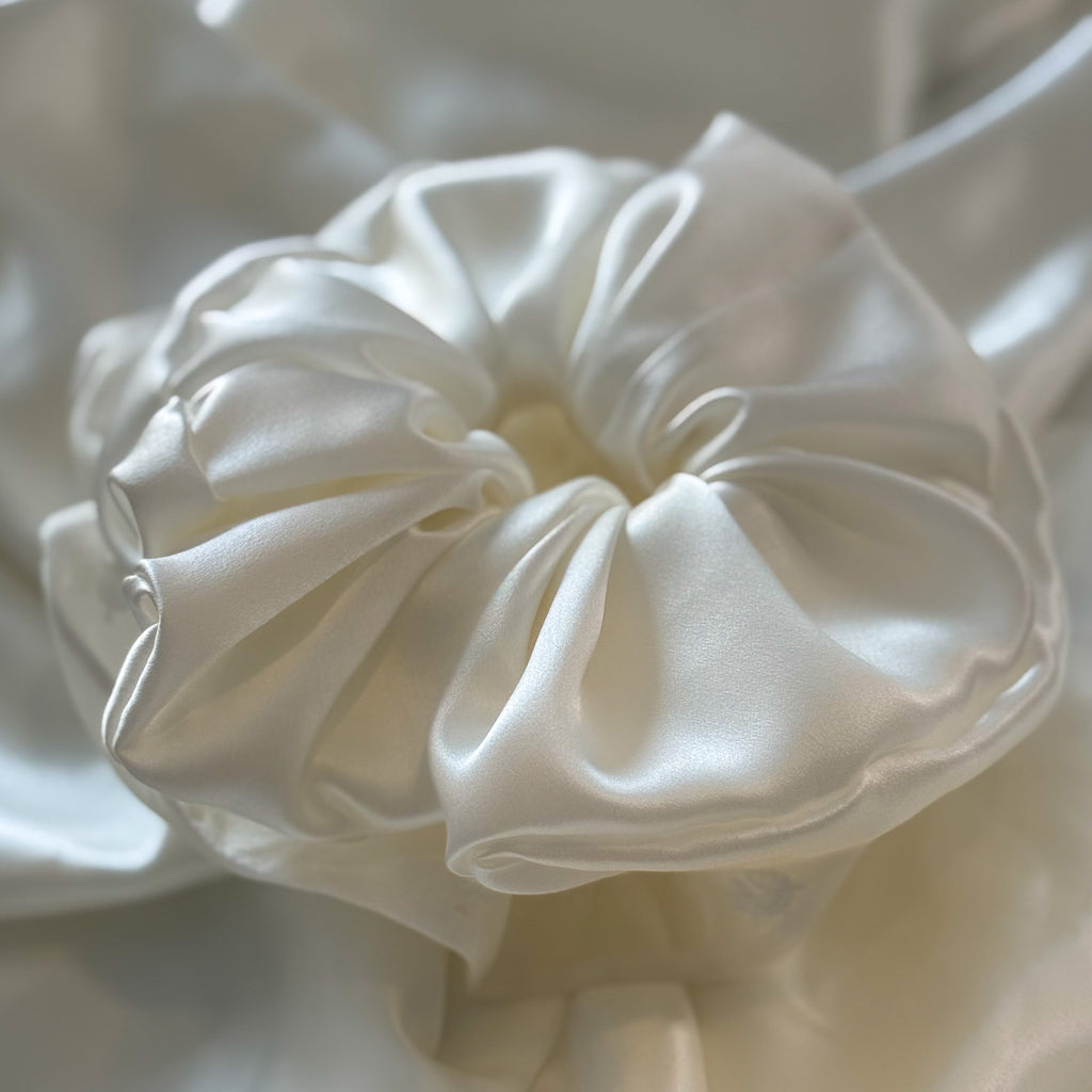 Close-up of a white satin scrunchie on a light background