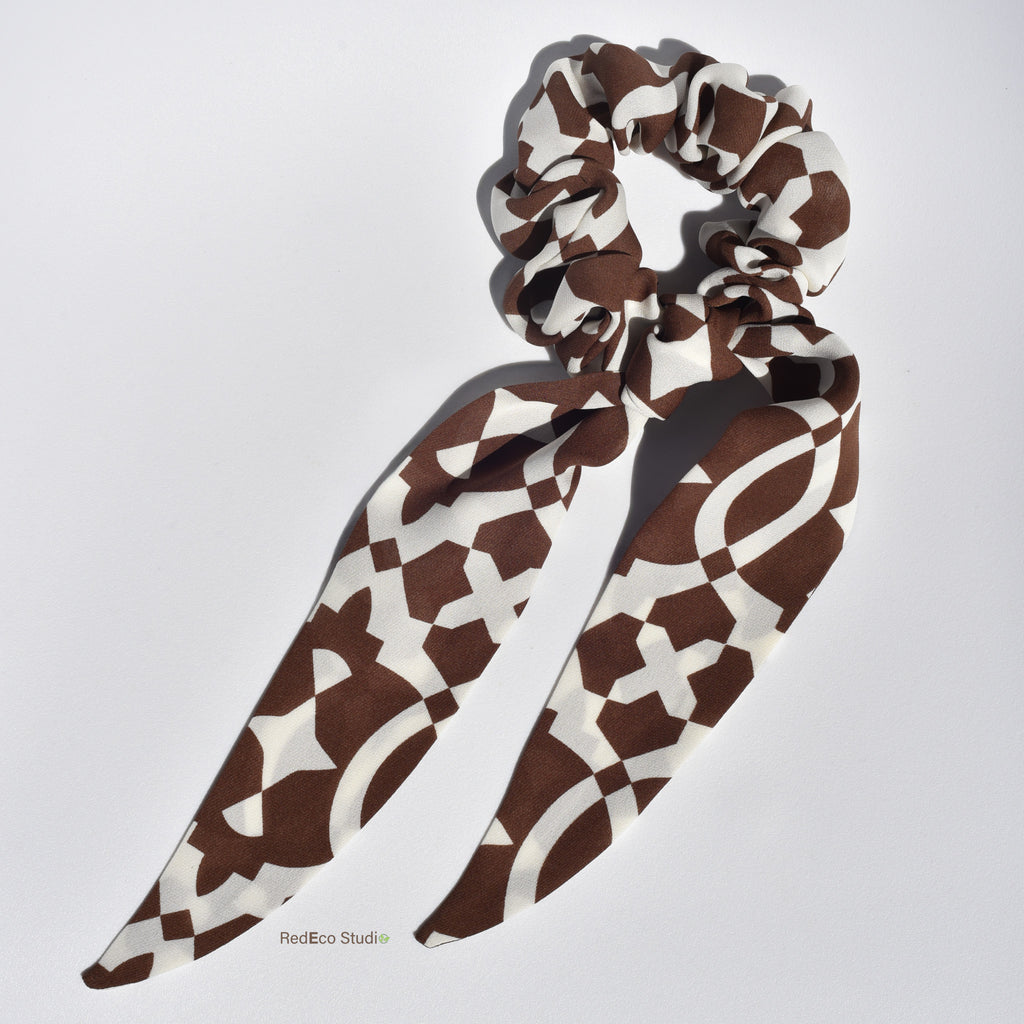 Classic brown and white patterned silk scrunchie with long tails on a light gray background