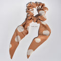 Medium brown and beige polka dot silk scrunchie with long tails on a white background