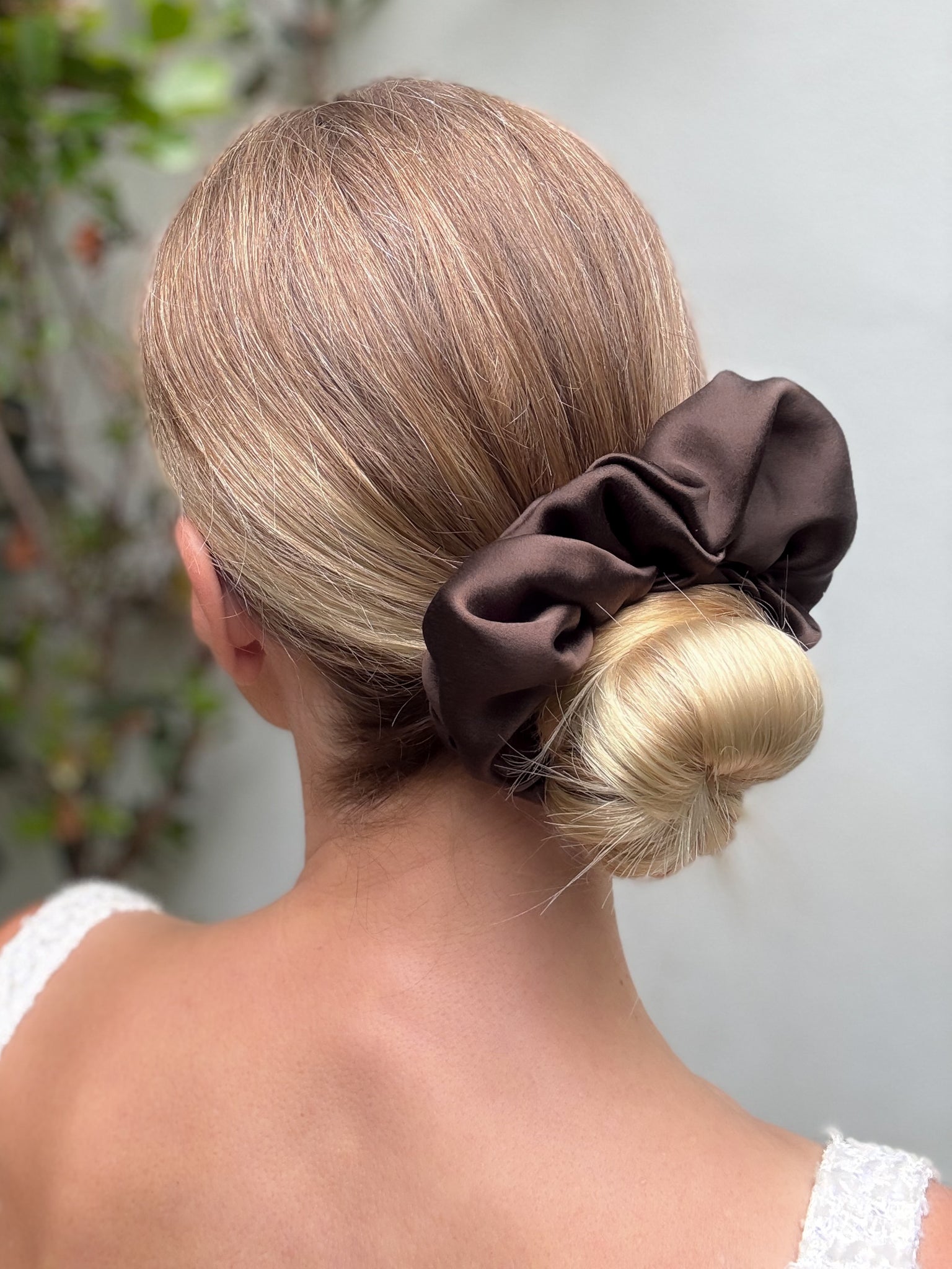 Brown scrunchie in a blonde bun against a neutral background