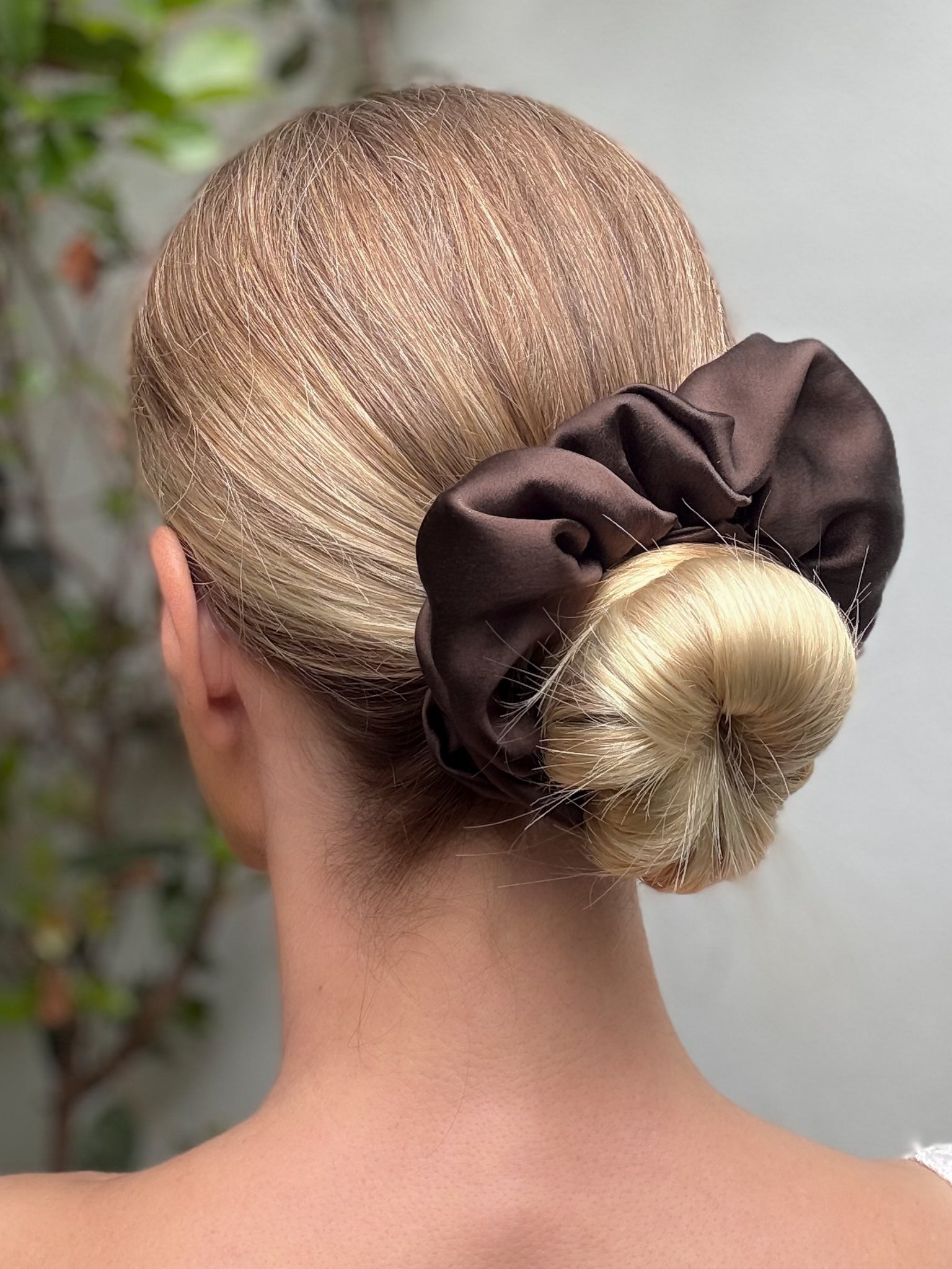 Brown scrunchie on a bun with a blurred background