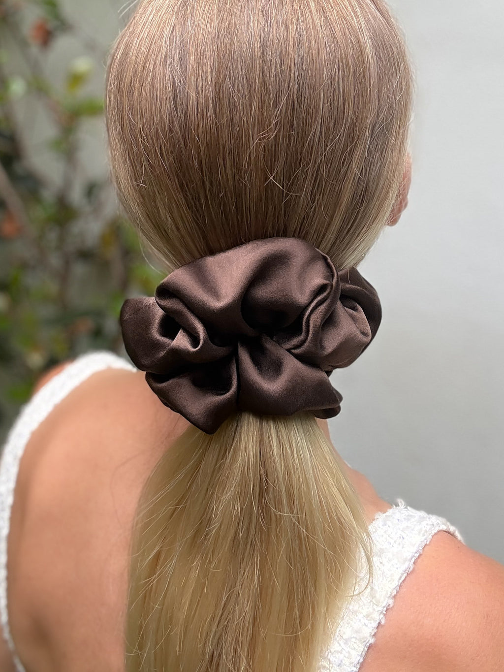 Brown scrunchie on a person's ponytail with a blurred background