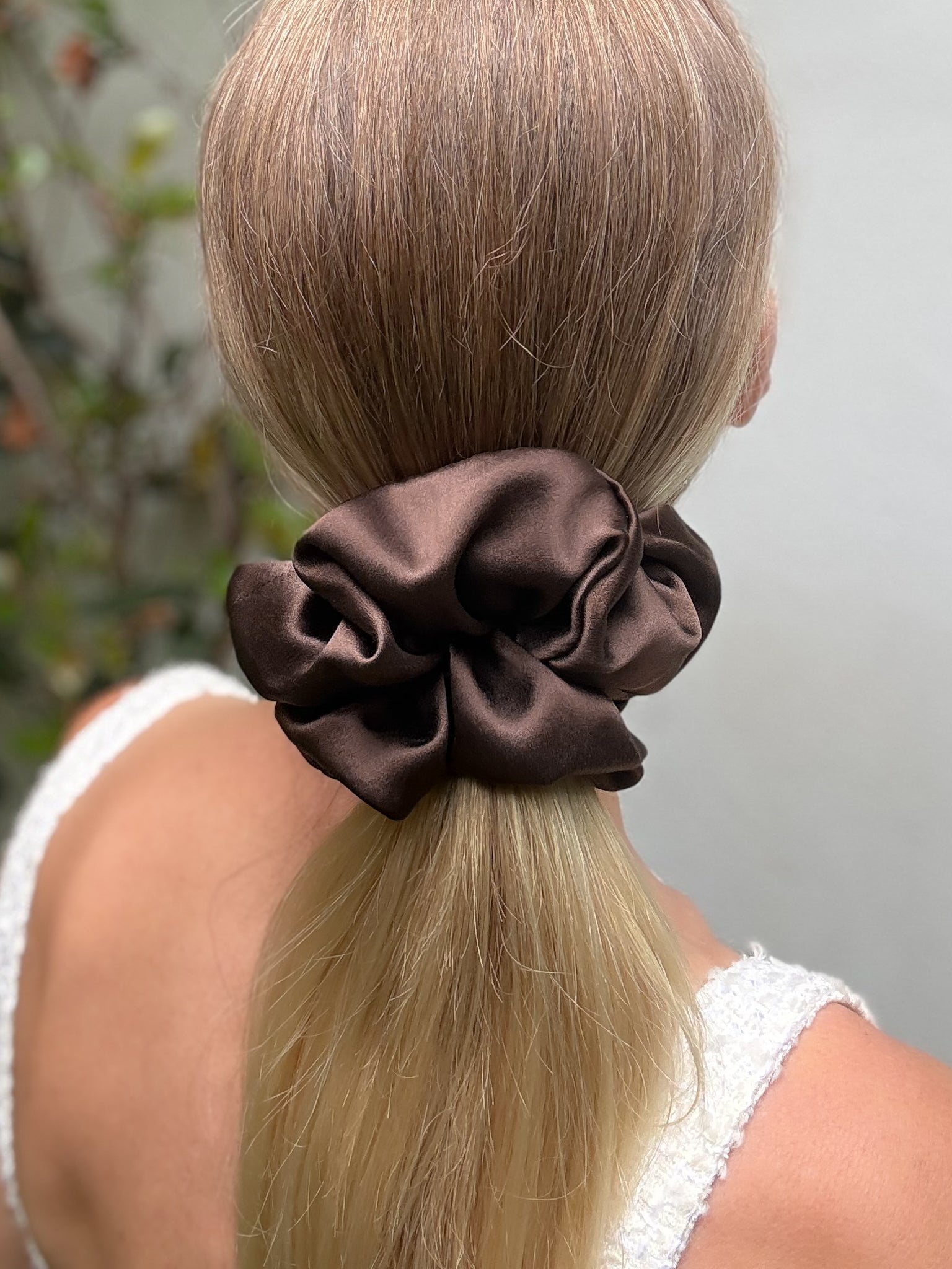 Brown scrunchie on a person's ponytail with a blurred background