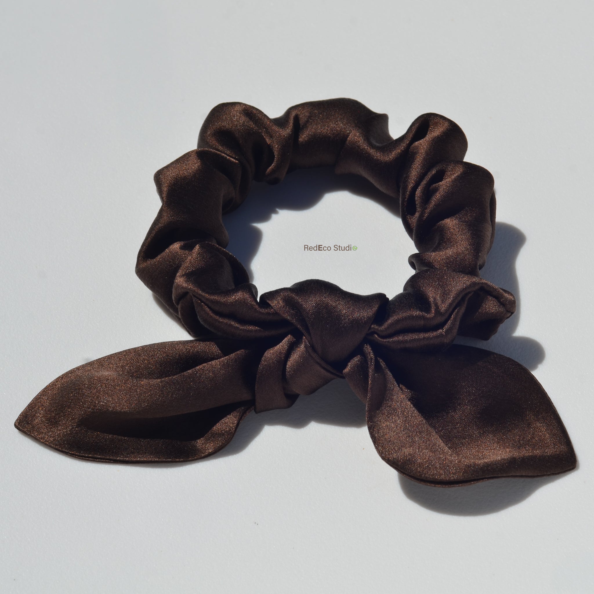 Brown scrunchie with a bow on a light gray background