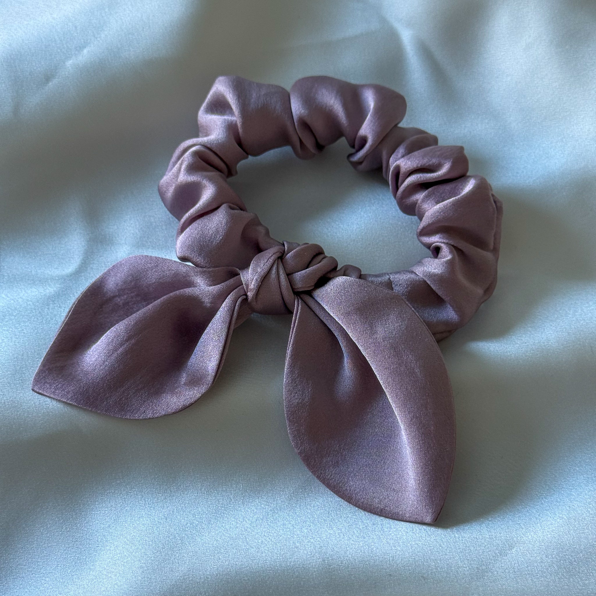 Pink scrunchie with a bow on a light gray background