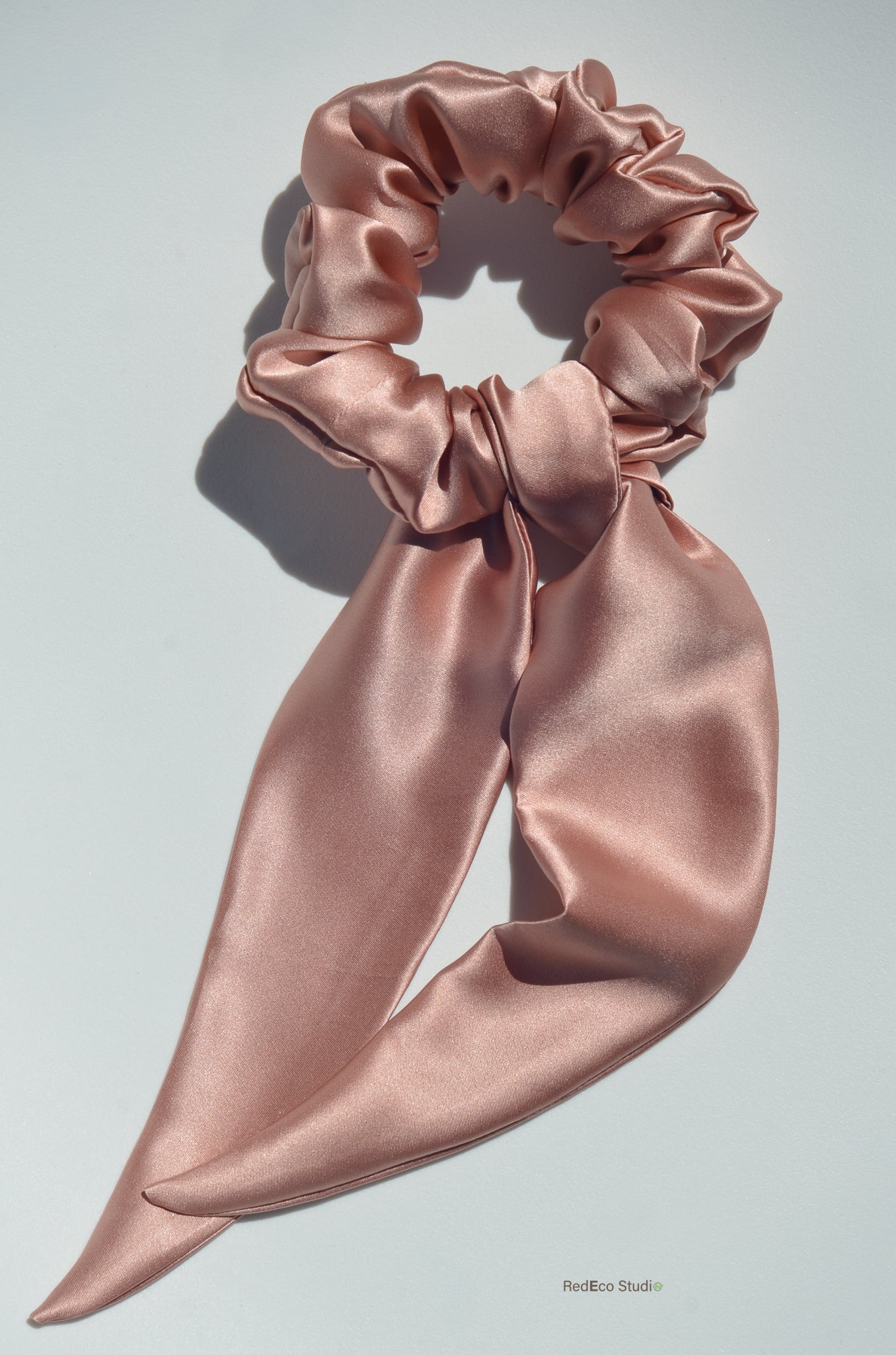 Pink satin hair scrunchie on a light gray background