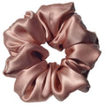 Pink satin scrunchie on a light gray background