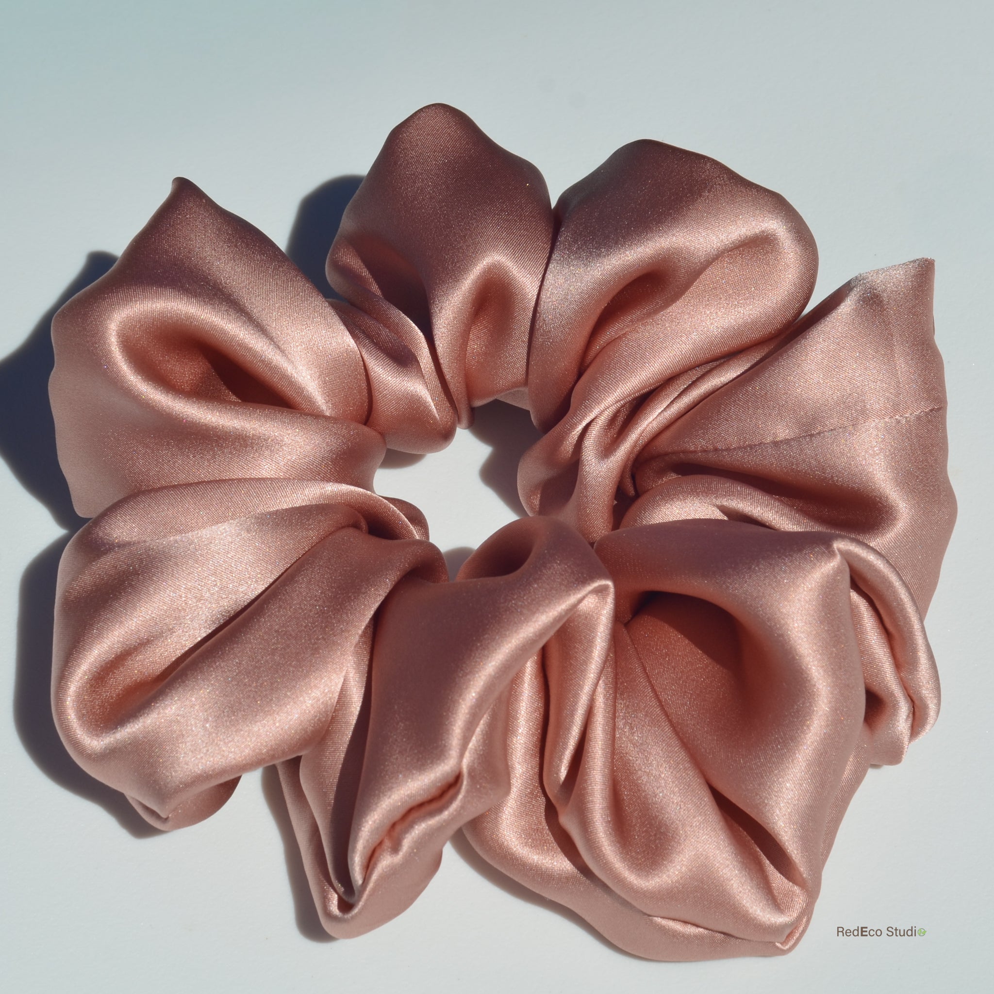 Pink satin scrunchie on a light gray background