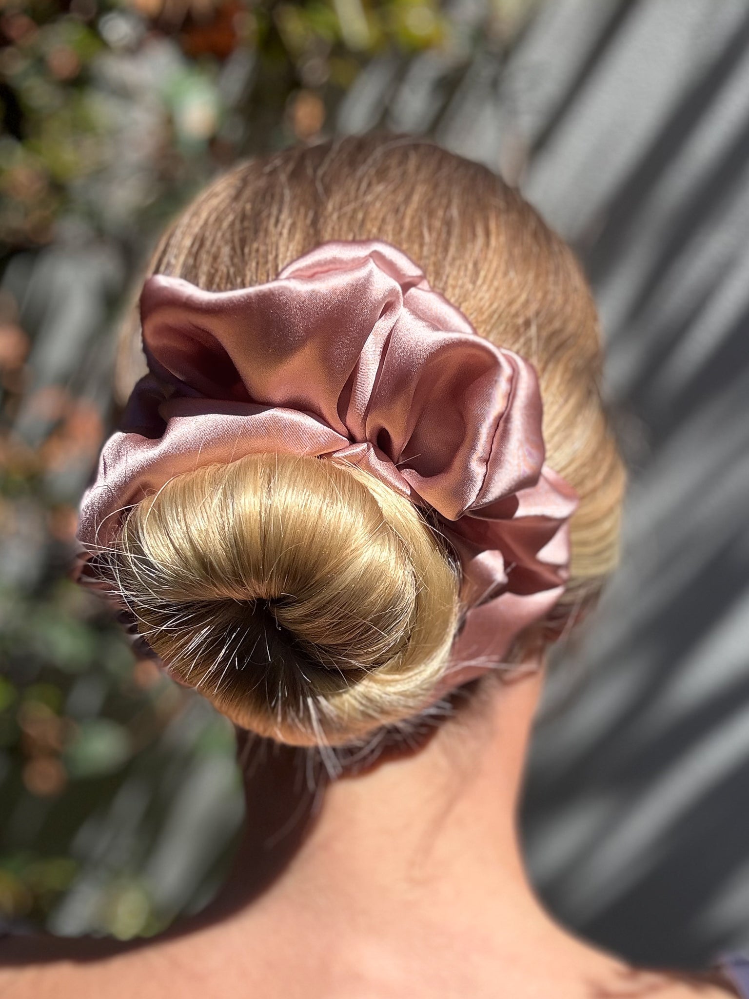 Pink scrunchie on a bun with blurred background