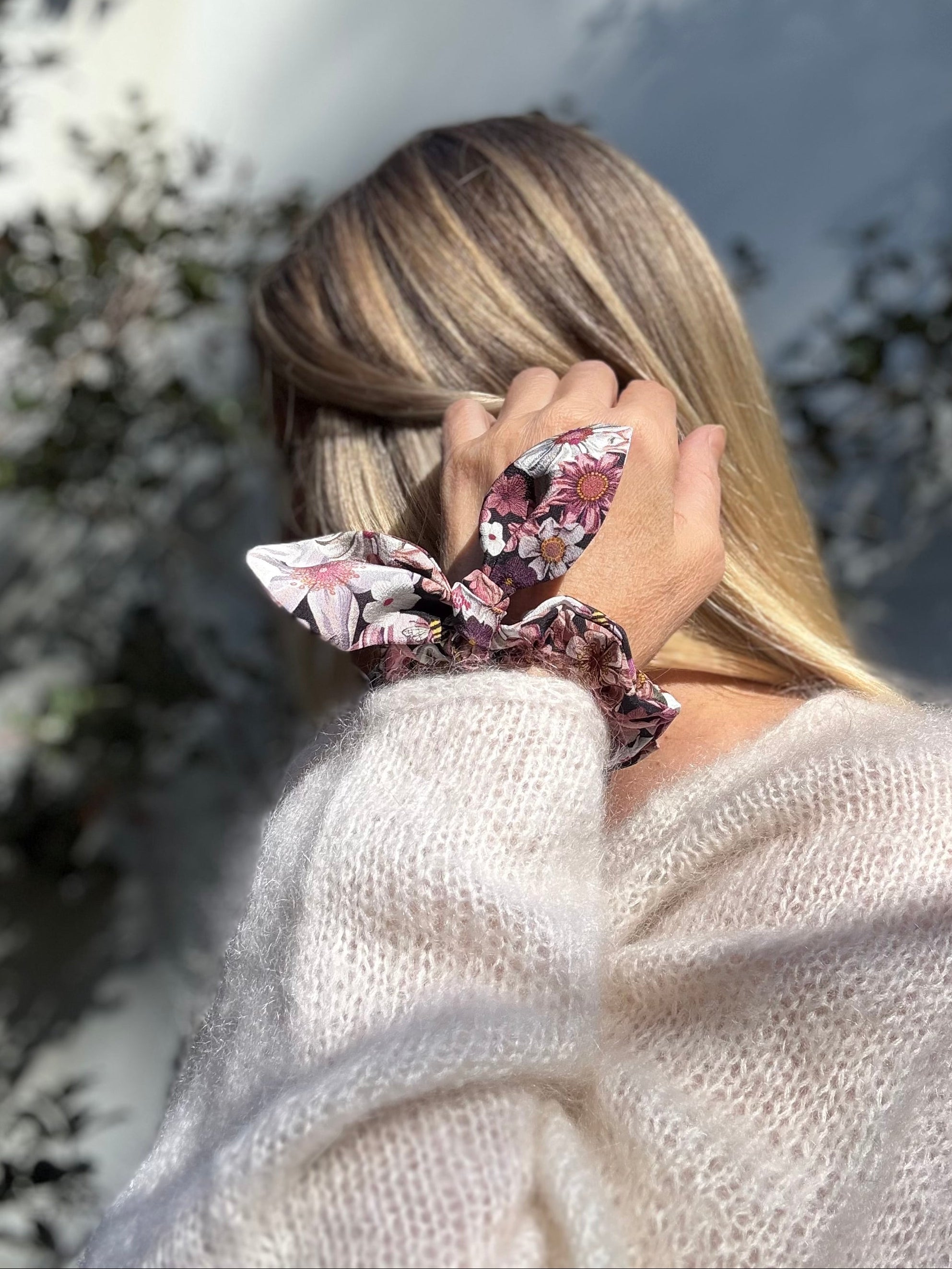 Person wearing a floral silk scrunchie around their wrist.