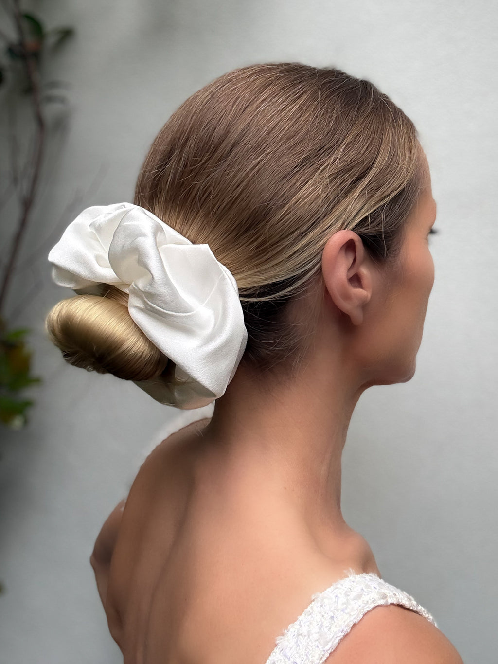 Woman with a white scrunchie in her hair against a neutral background