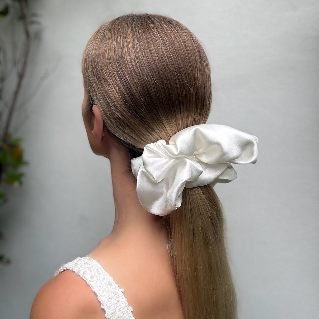 Woman with a white scrunchie in her hair against a light gray background