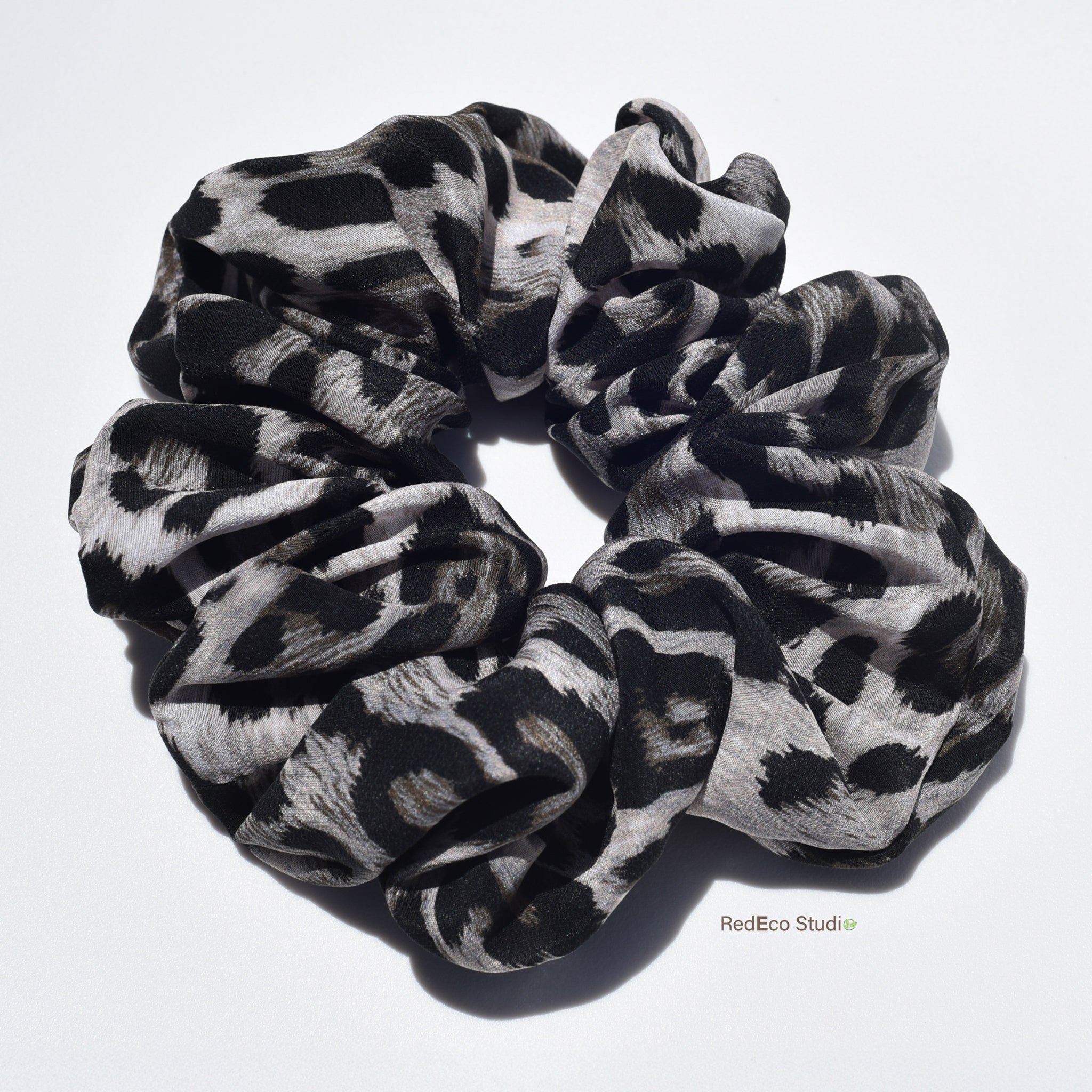 Large leopard patterned silk scrunchies on a white background