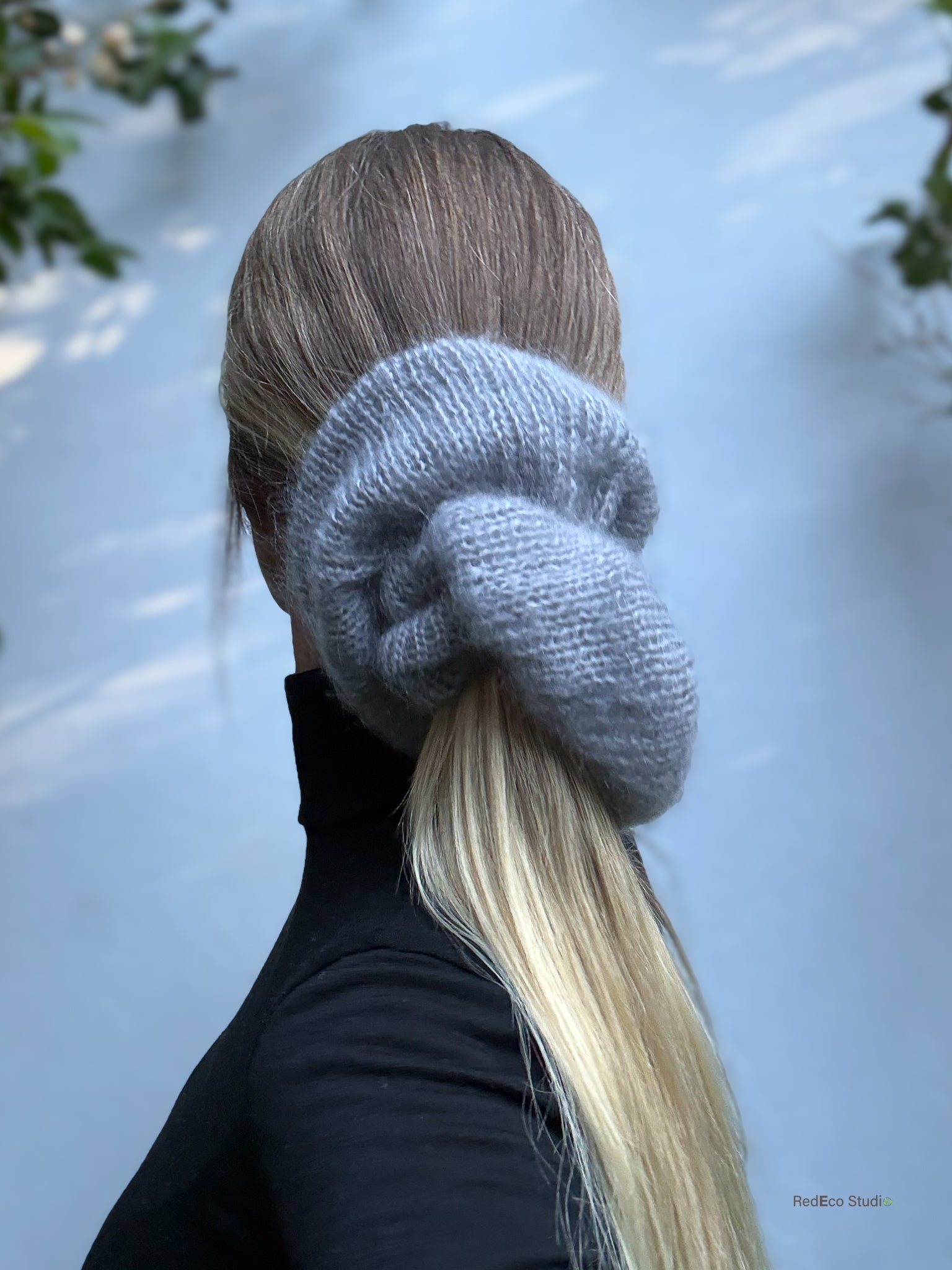 Person wearing a gray knitted scrunchie on a blurred natural background