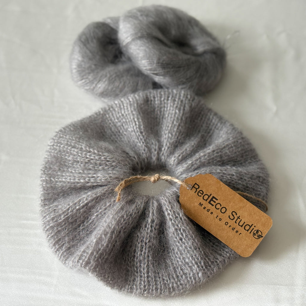 Gray knitted scrunchie with a tag on a light gray background
