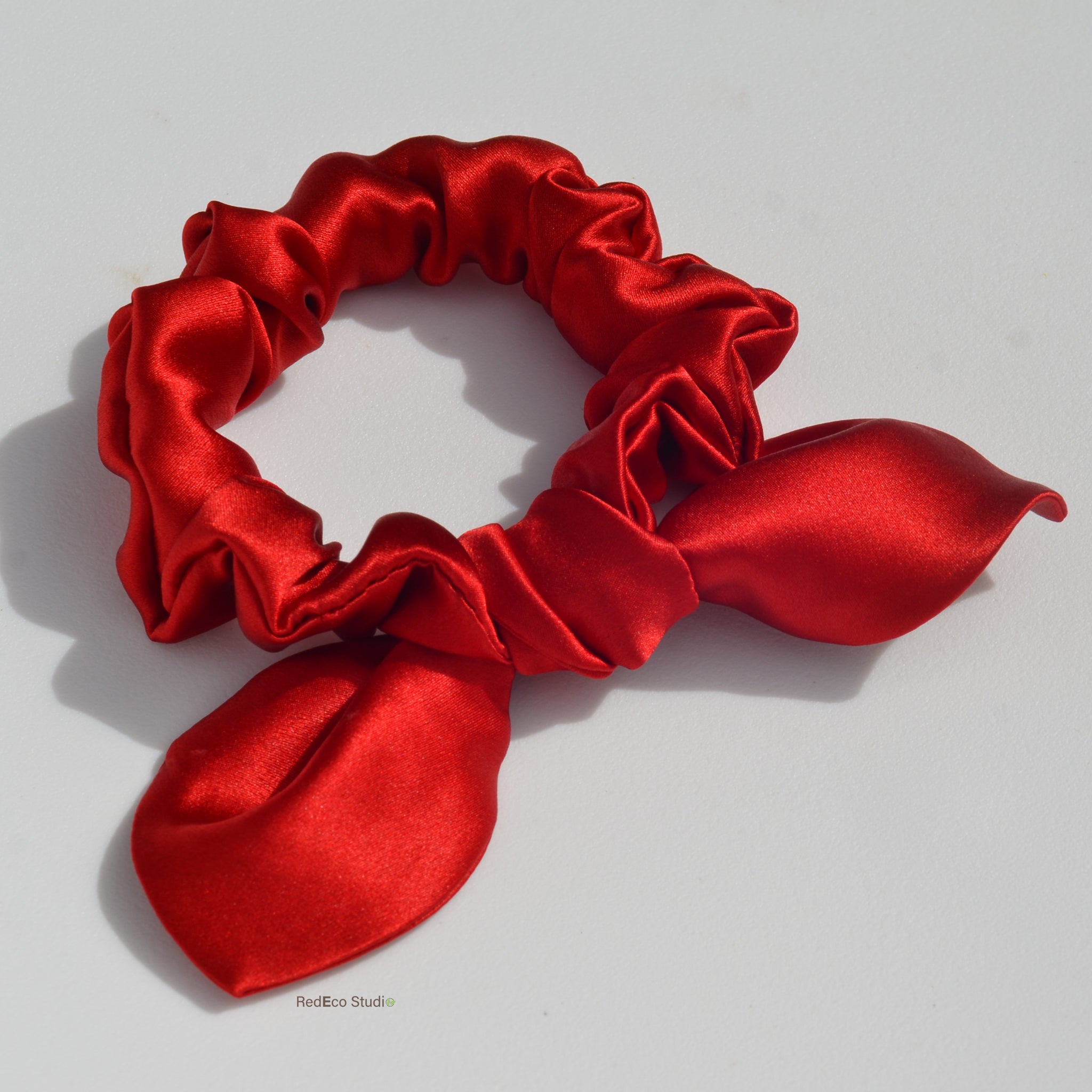 Red satin scrunchie on a light gray background