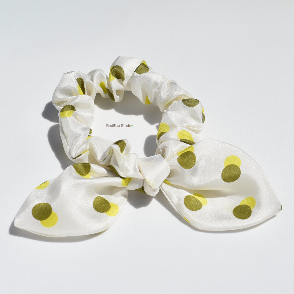 White scrunchie with green polka dots on a white background