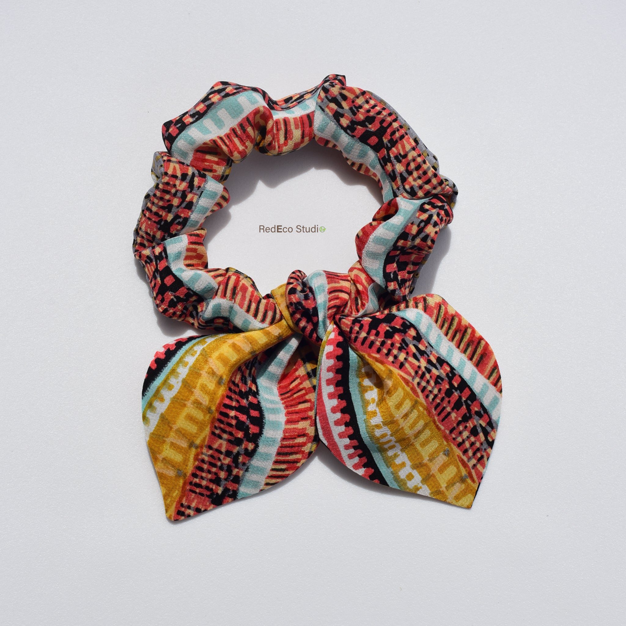 Mini colorful patterned silk scrunchie  with bow on a light gray background