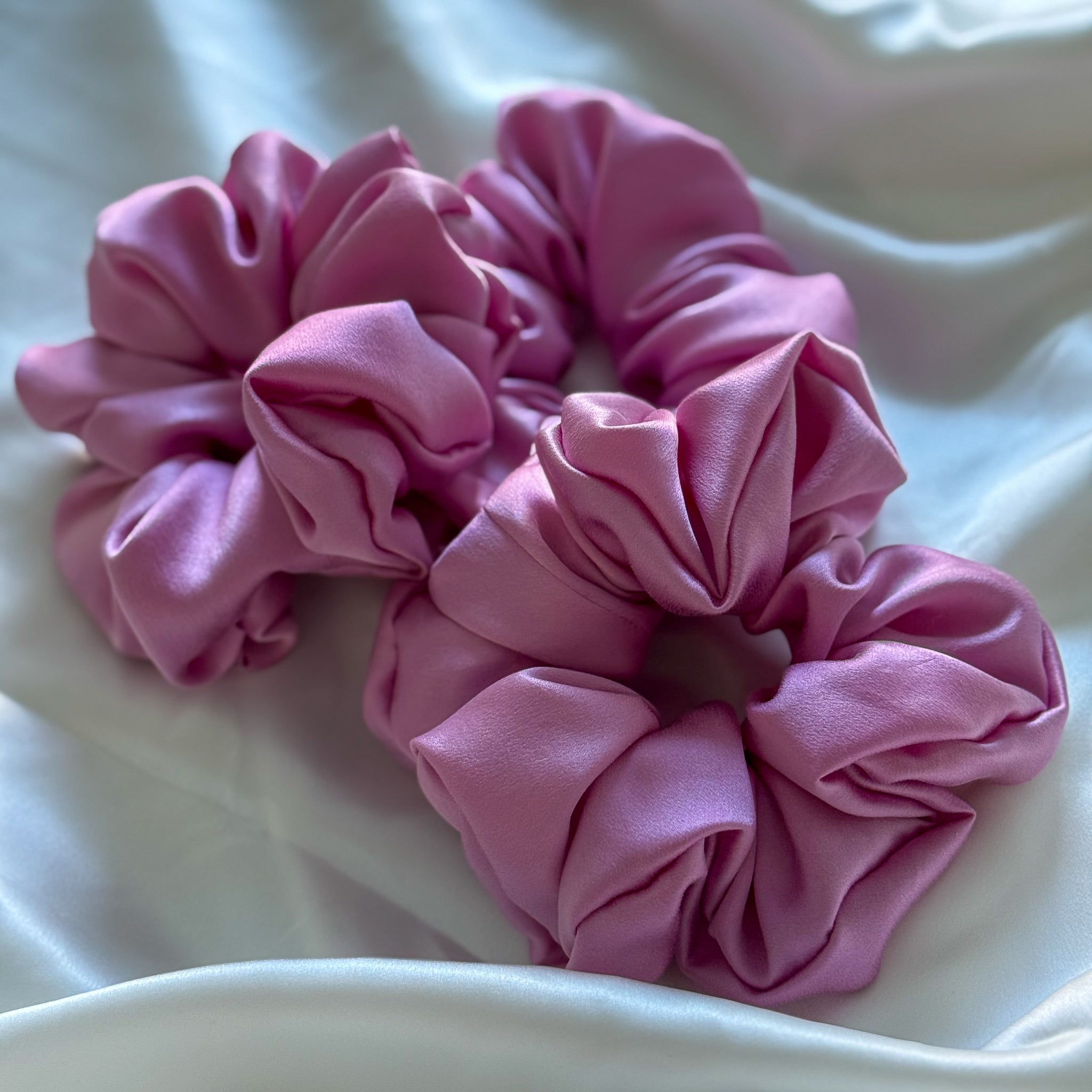 Two pink scrunchies on a white surface