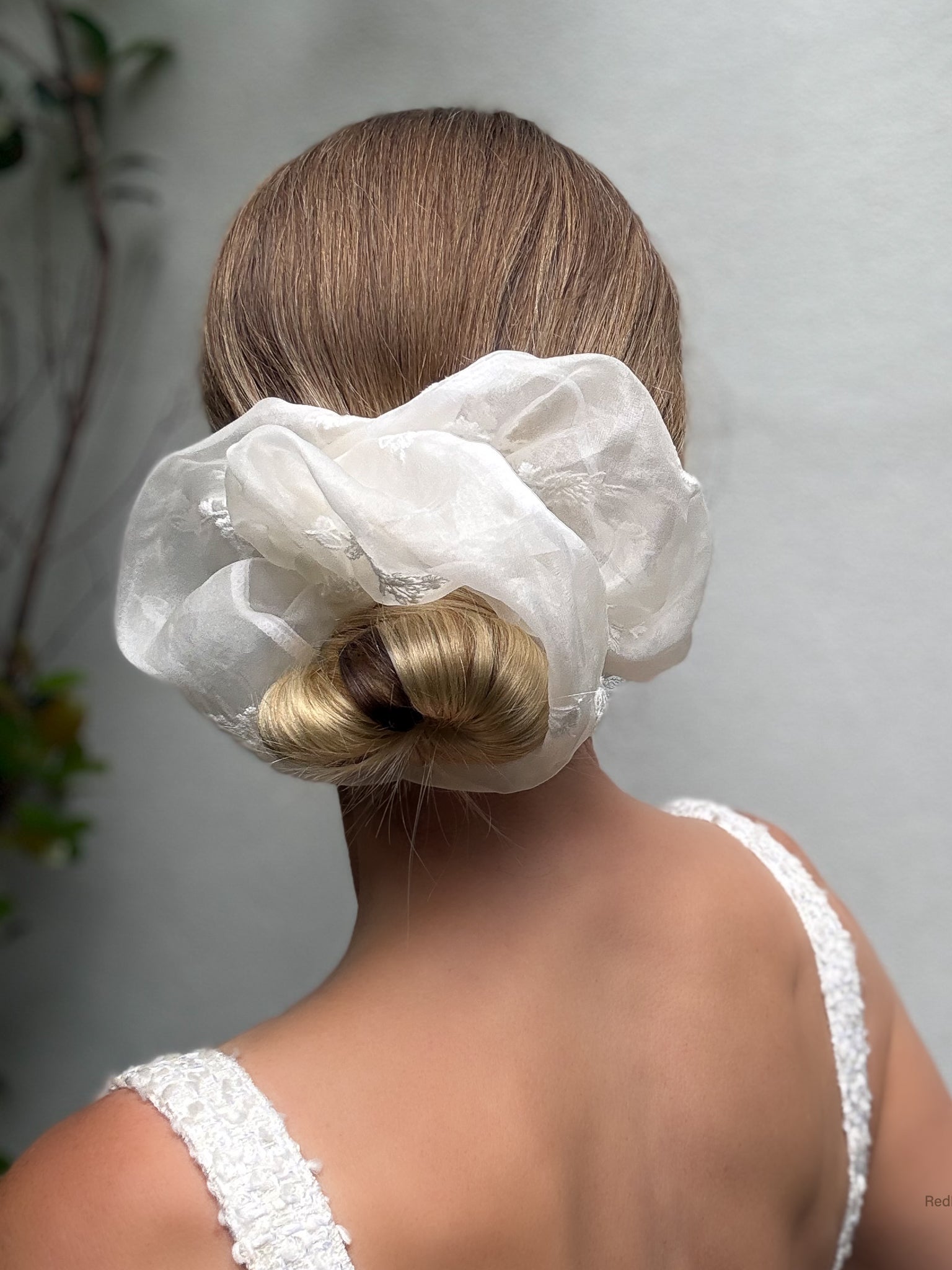 Person with a white hair scrunchie on a plain background