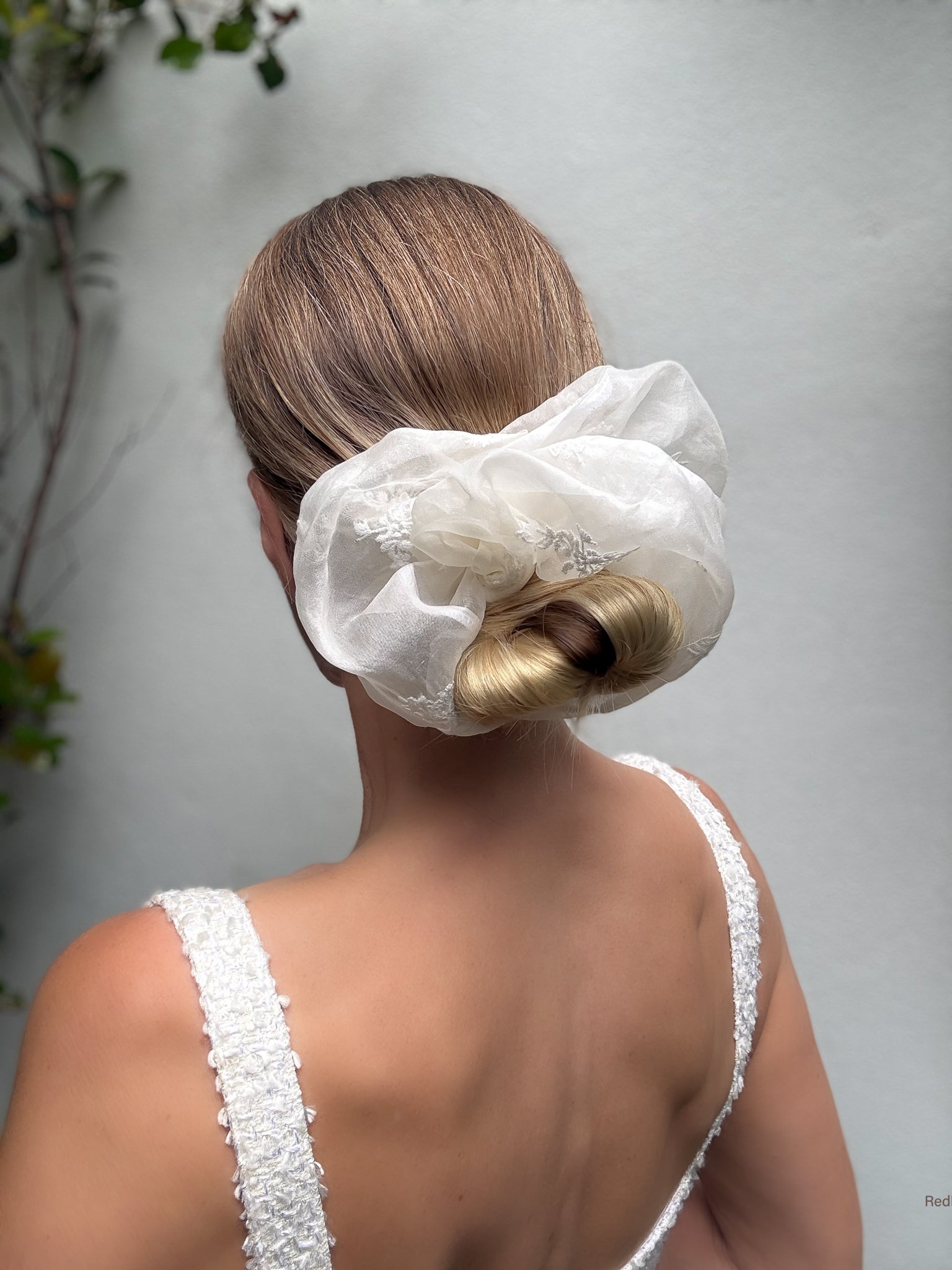 Woman with a large white hair bow styled in her hair against a neutral background