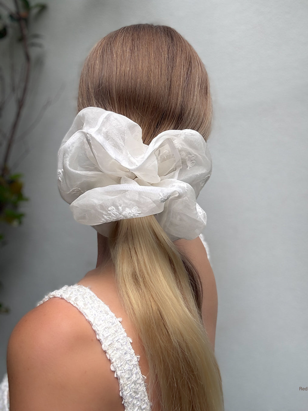 Person with a white lace hair scrunchie on a plain background