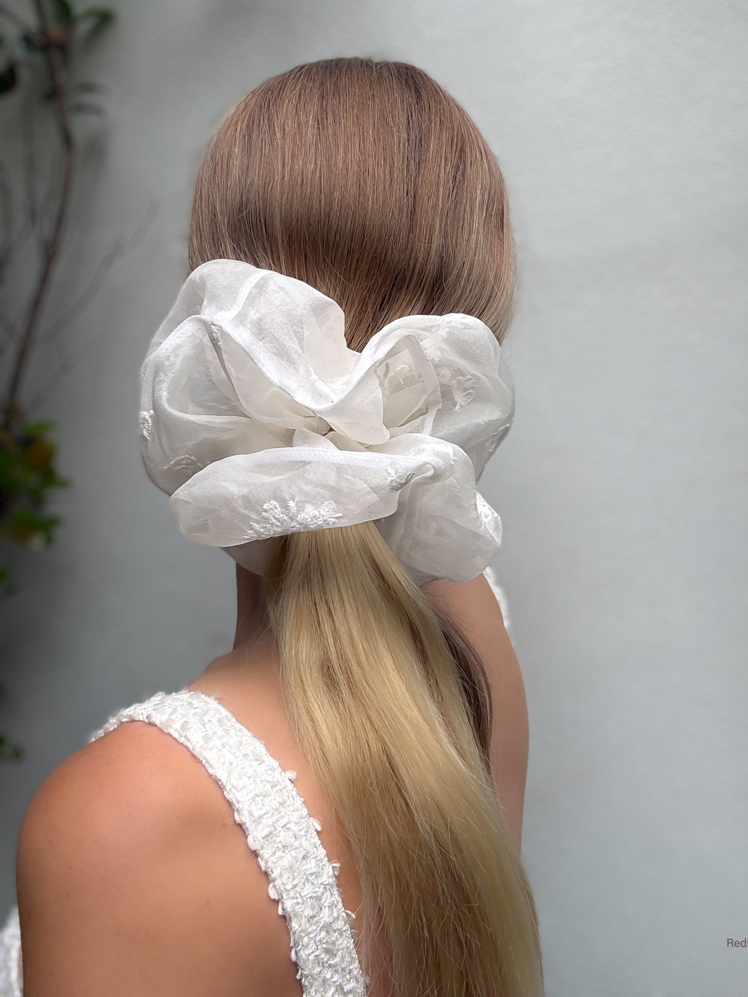 Person with a white lace hair scrunchie on a plain background