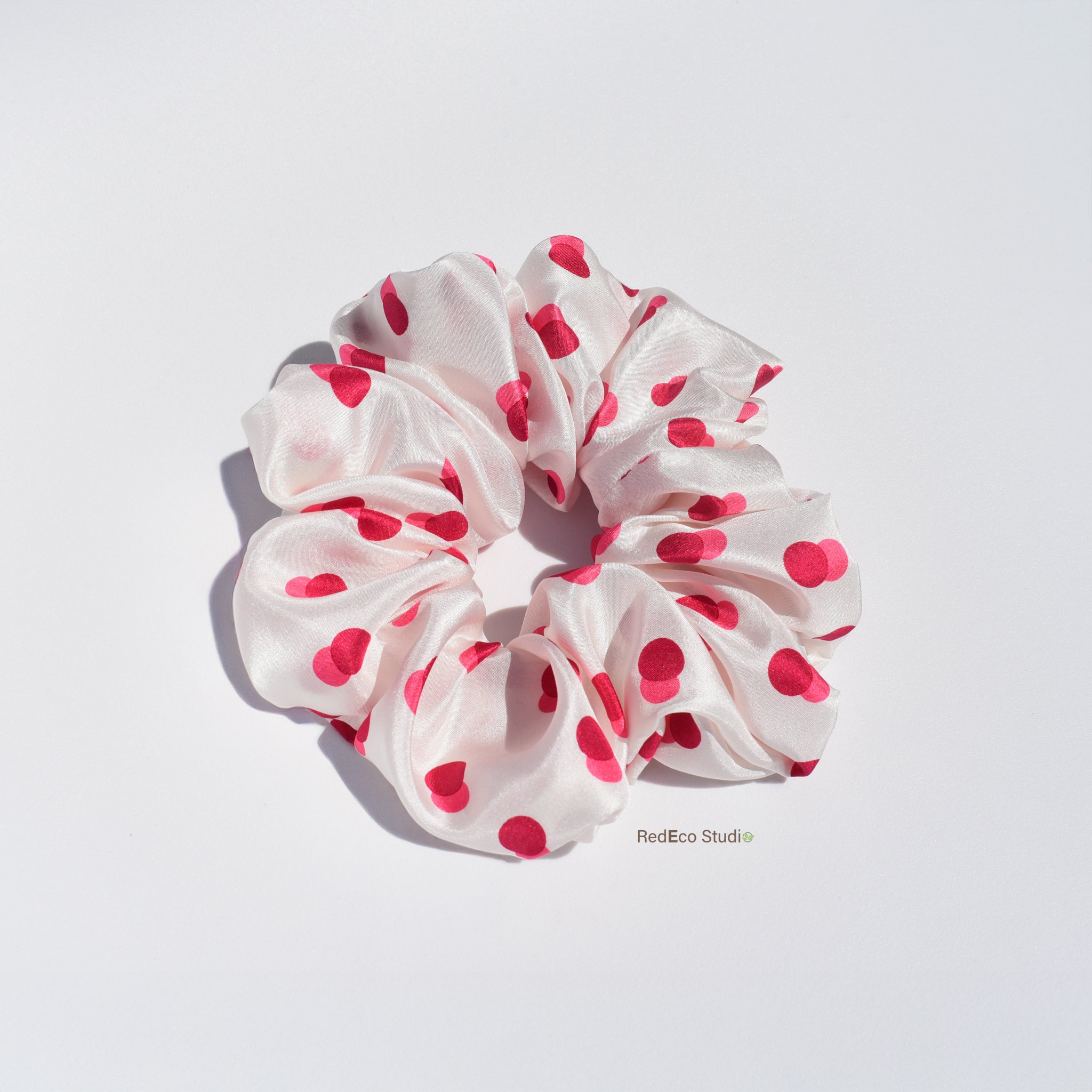 White silk scrunchie with two-tone red spots on a white background