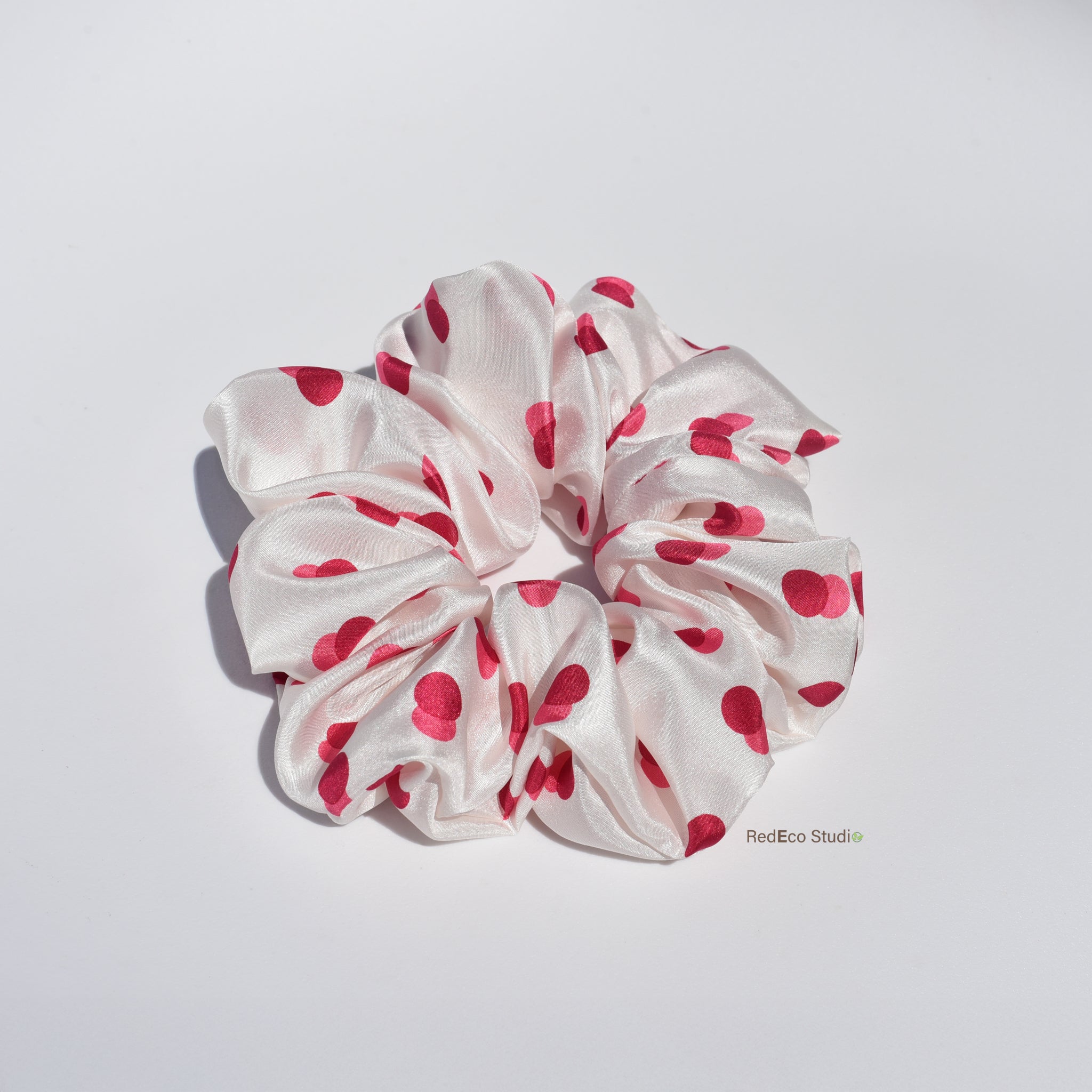White silk scrunchie with two-tone red spots on a white background
