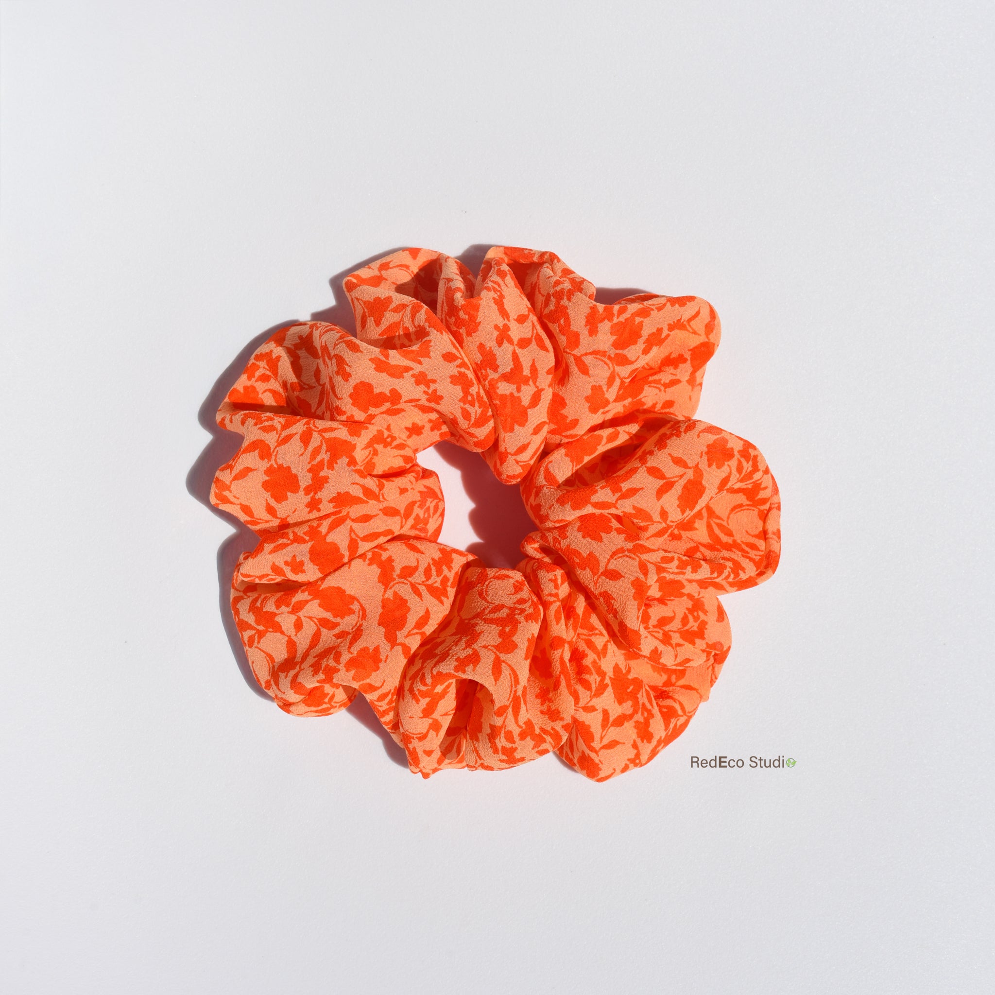 Orange floral silk scrunchie on a white background