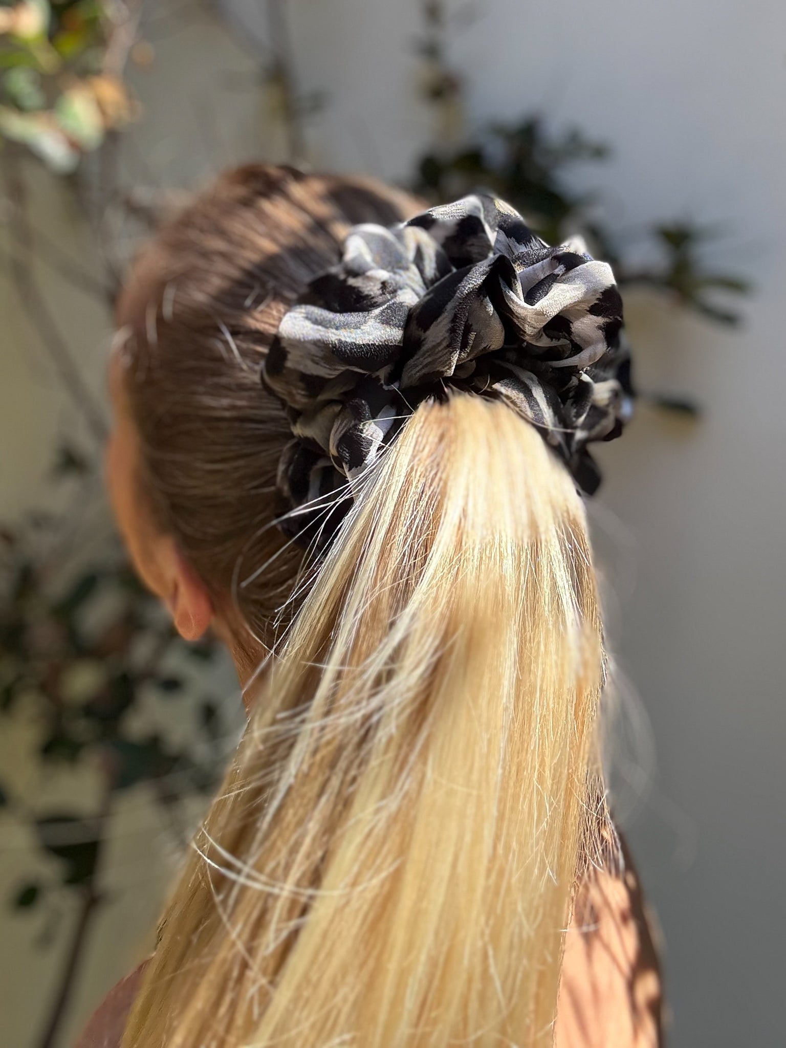 Person with a black and white patterned scrunchie in their hair, with a blurred background.