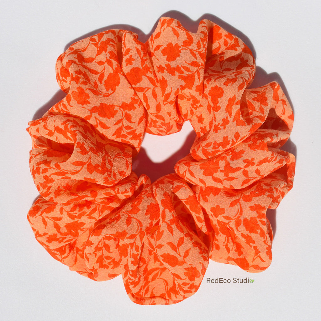 Orange floral silk scrunchie on a white background