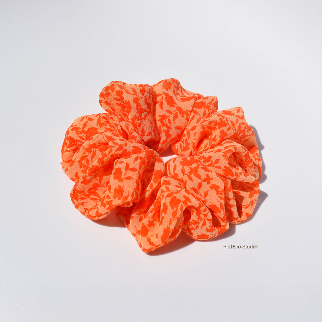 Orange floral silk scrunchie on a white background