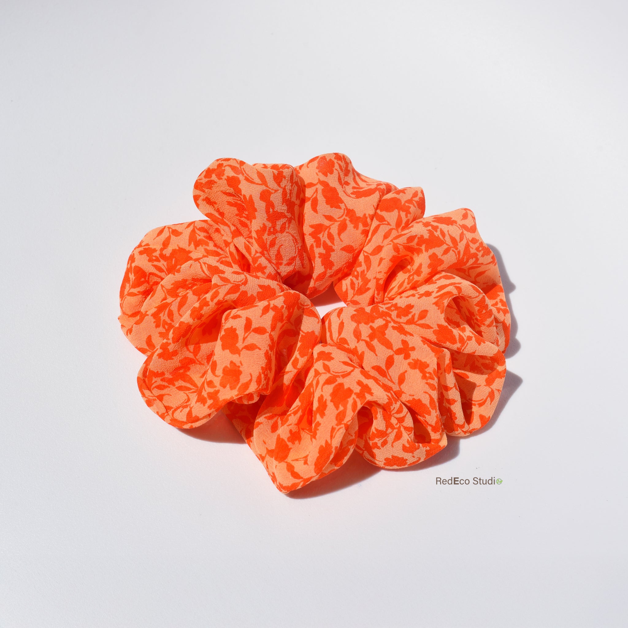 Orange floral silk scrunchie on a white background