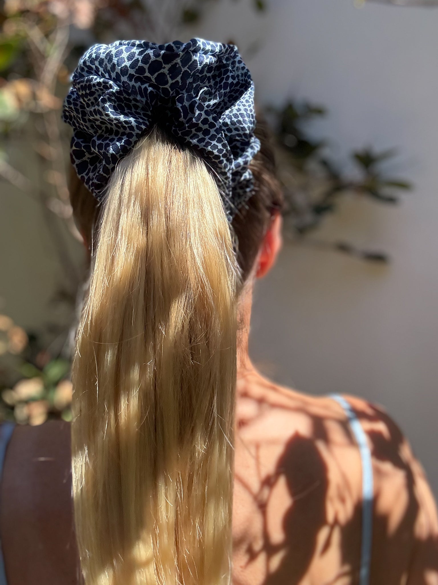 Person with a blue patterned hair tie in their blonde hair, outdoors.