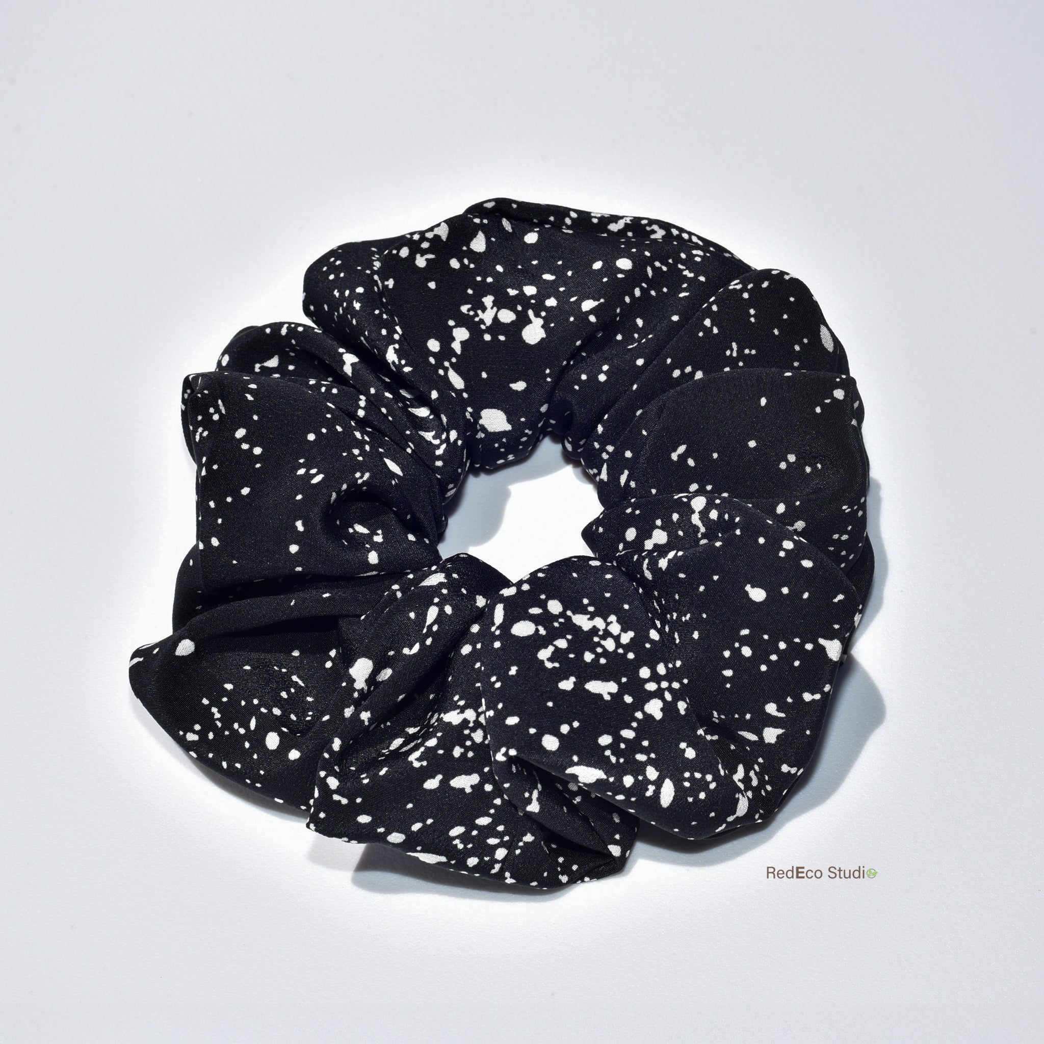 Black scrunchie with white speckles on a light gray background