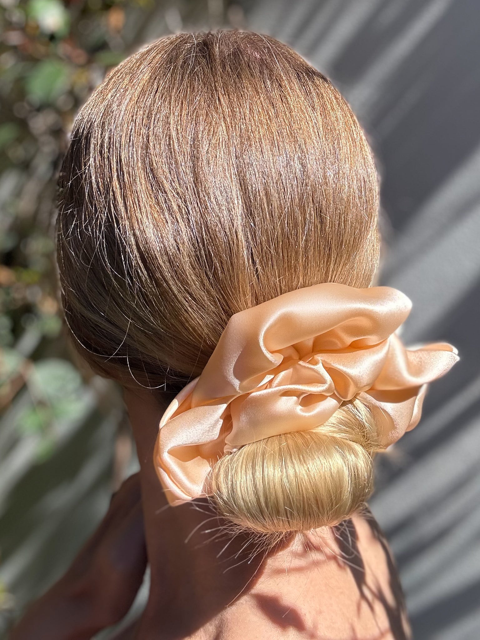 Person with a peach-colored scrunchie in their hair, outdoors.