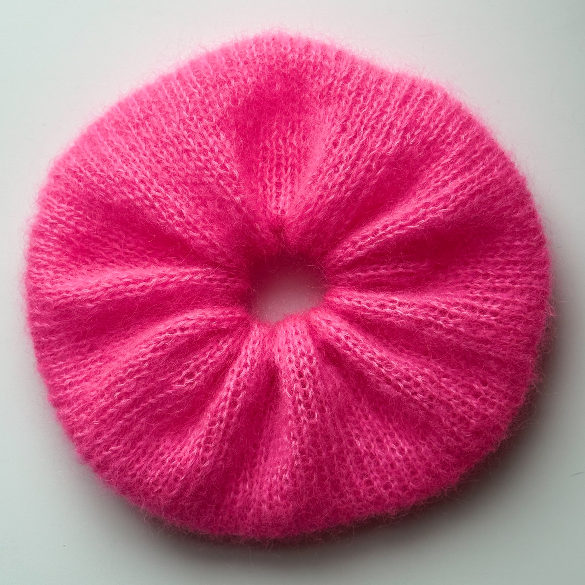 Extra large hand-knitted scrunchie in bright pink on a white background