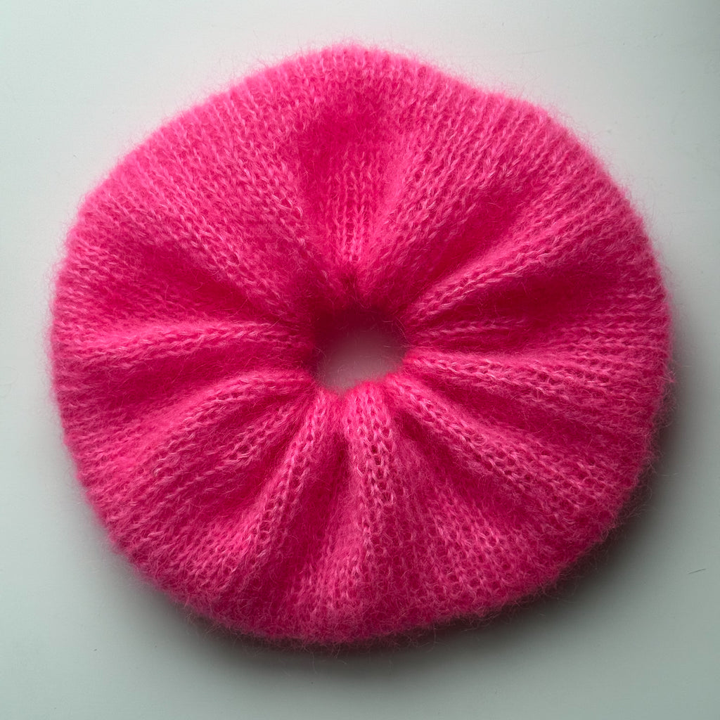 Oversized pink knitted scrunchie on a white background