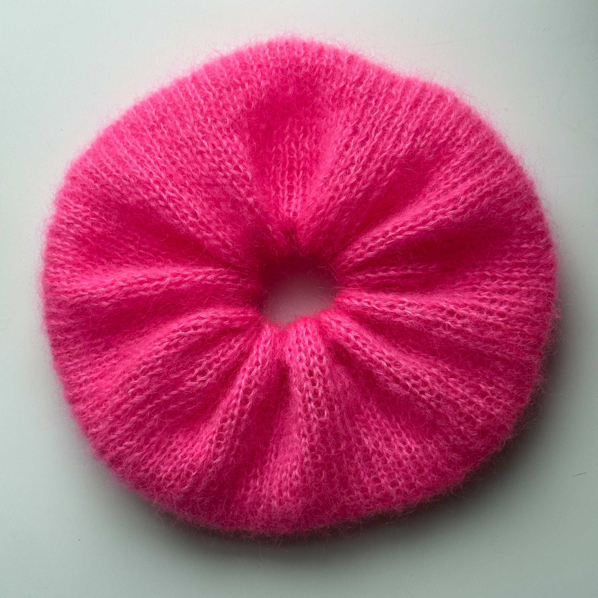 Oversized pink knitted scrunchie on a white background