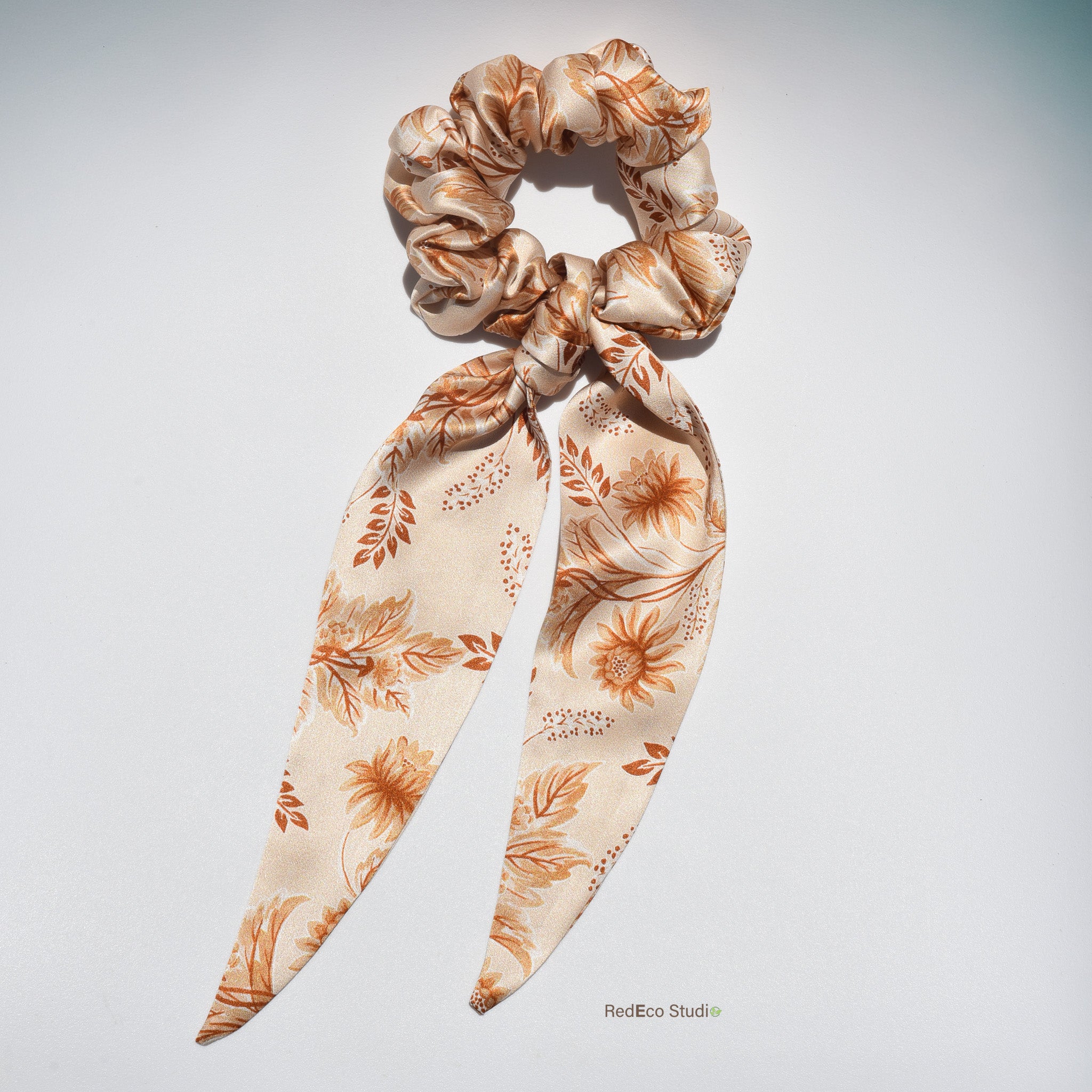 Floral patterned silk scrunchie with long tails on a light gray background