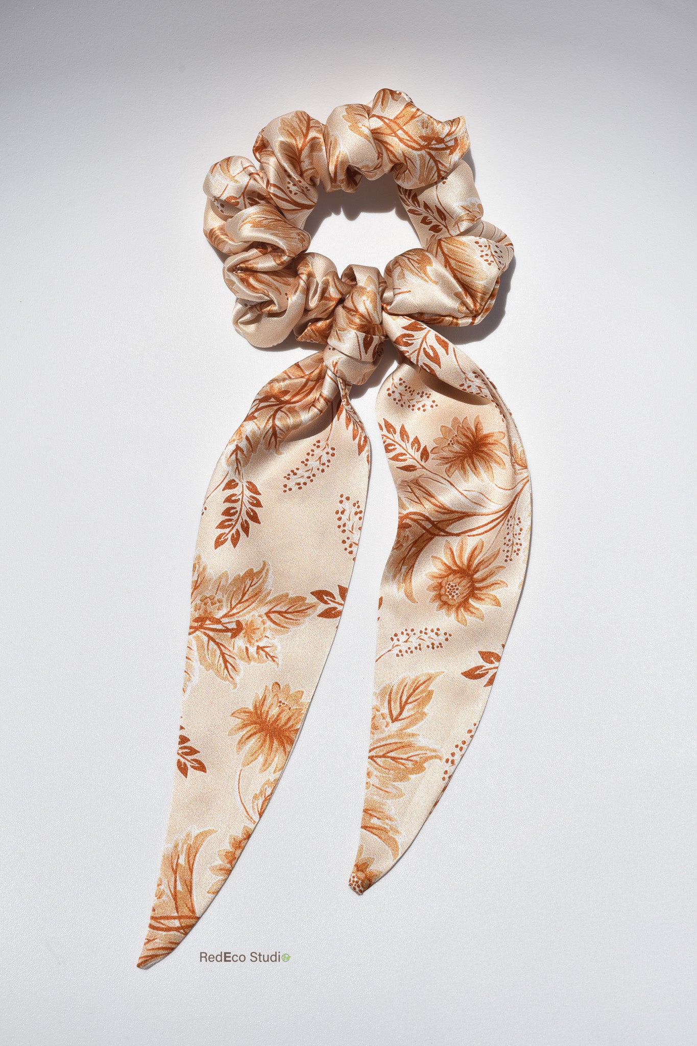 Floral patterned silk scrunchie with long tails on a light gray background