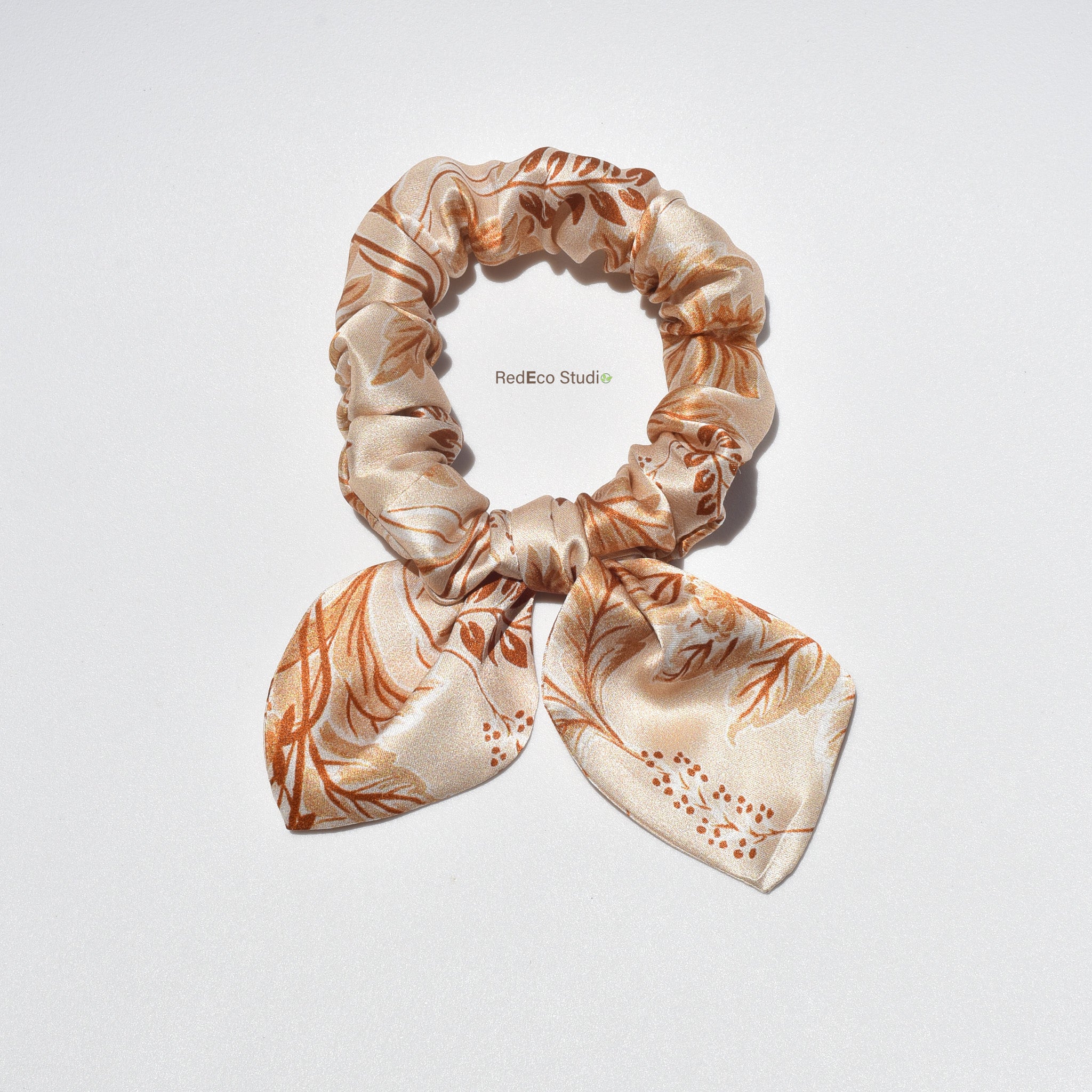 Floral patterned silk scrunchie with bow on a light gray background