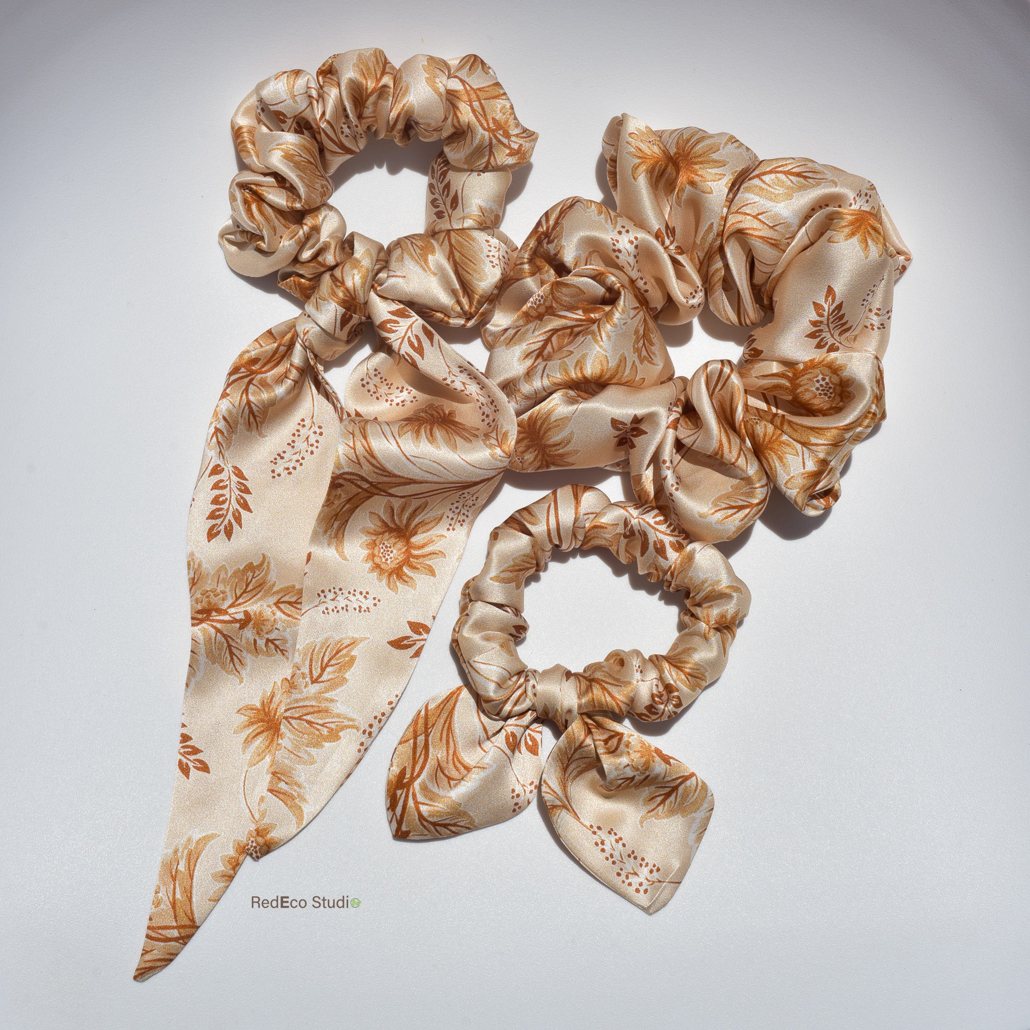Set of beige floral silk scrunchies on a light gray background