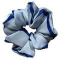 A large silk hair scrunchie with alternating light blue and royal blue stripes, photographed on a neutral light grey background.