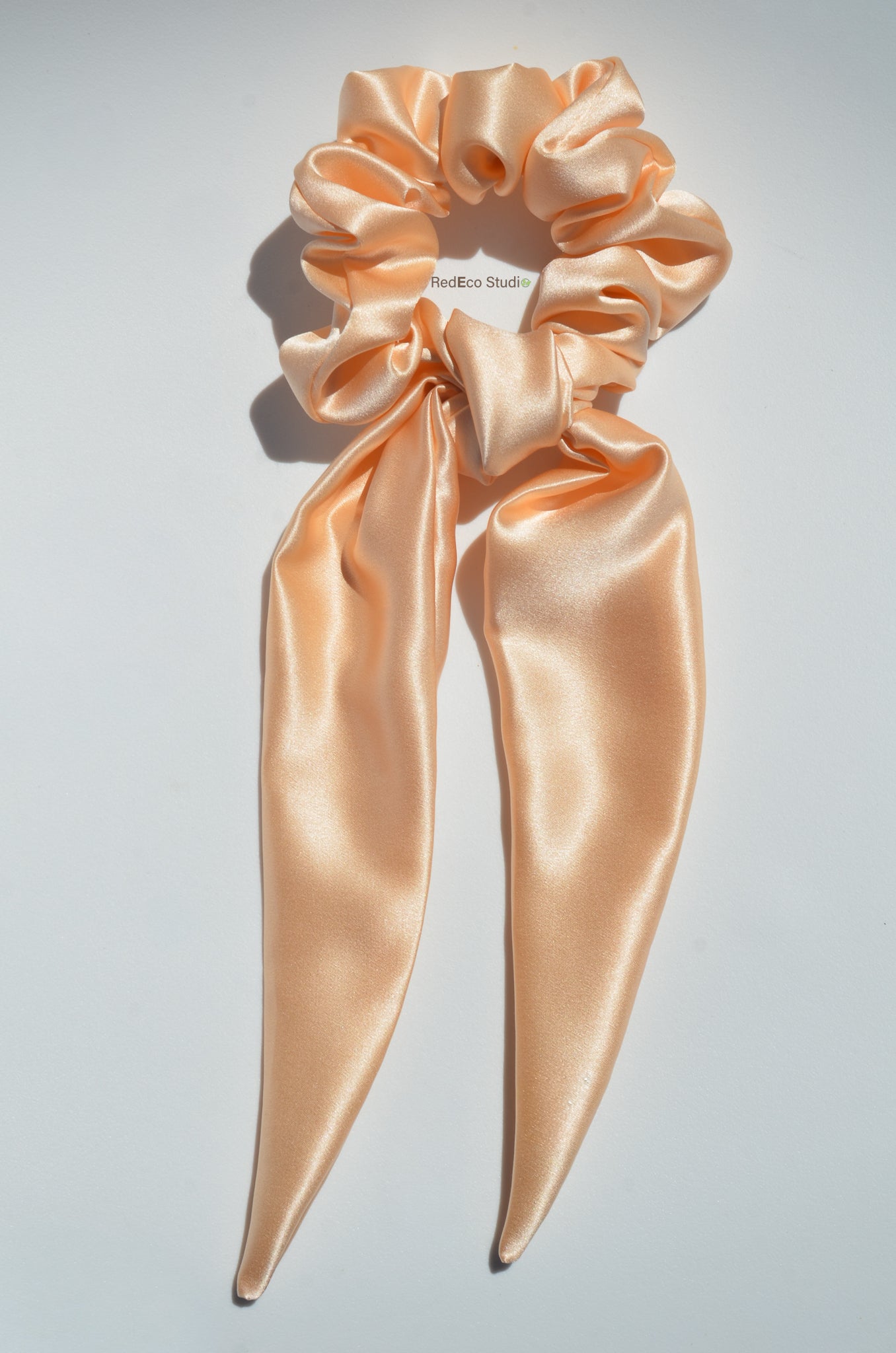 Silk scrunchie with long ribbons on a light gray background